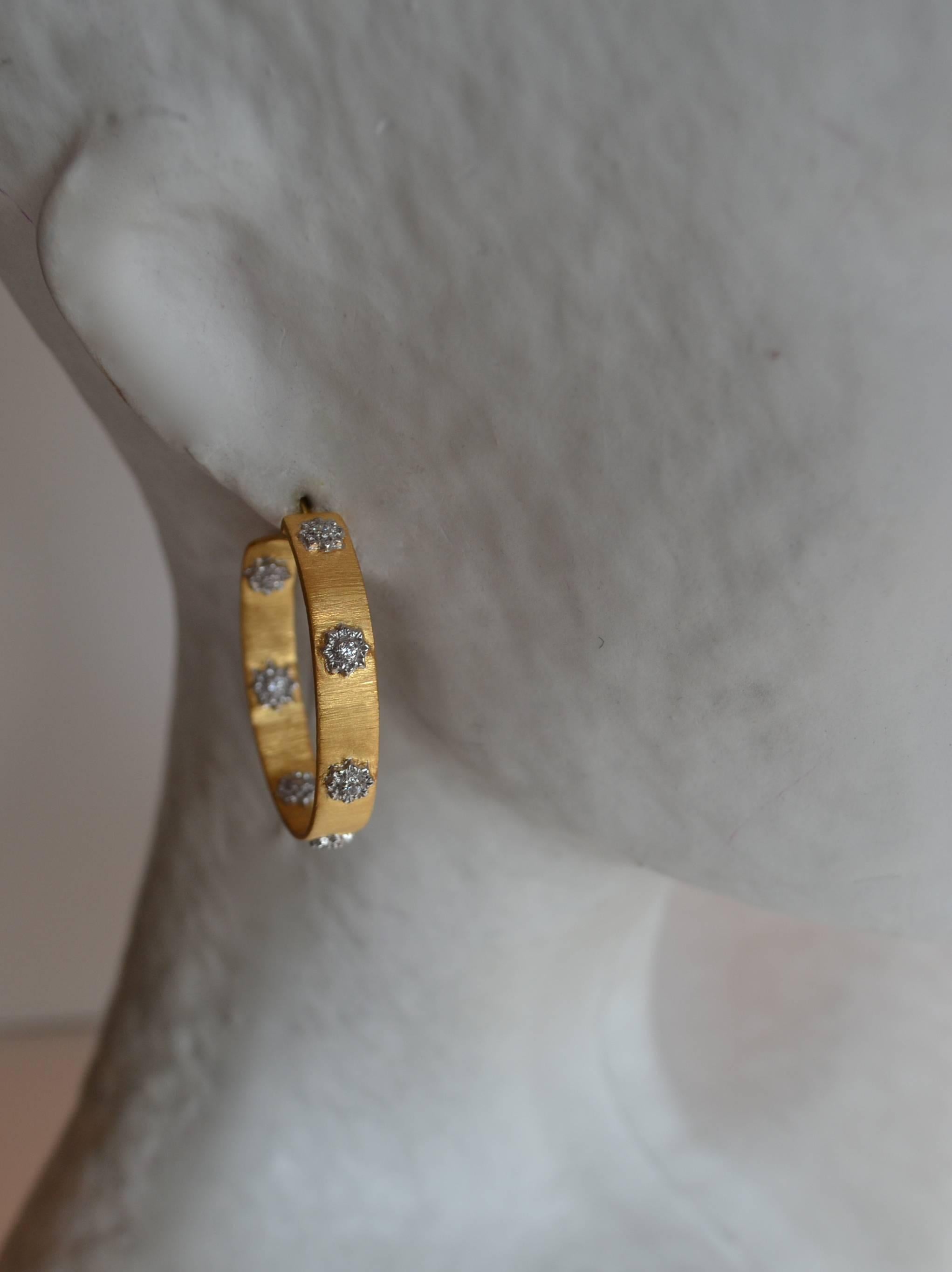 Pierced hoop earrings in gold and rhodium plate with gorgeous flower pattern and cubic zirconia detail. Made by Bijoux Num. 

