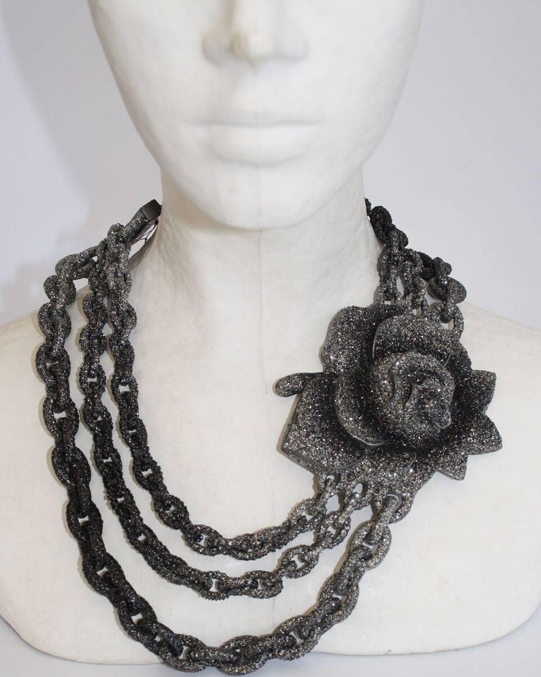Ombre grey to black graduated link chain necklace with beautiful flower station from KMO Paris. Made with their unique Kamelite process. Each piece is encrusted with genuine .925 sterling silver dust providing incredible shine and sparkle. 