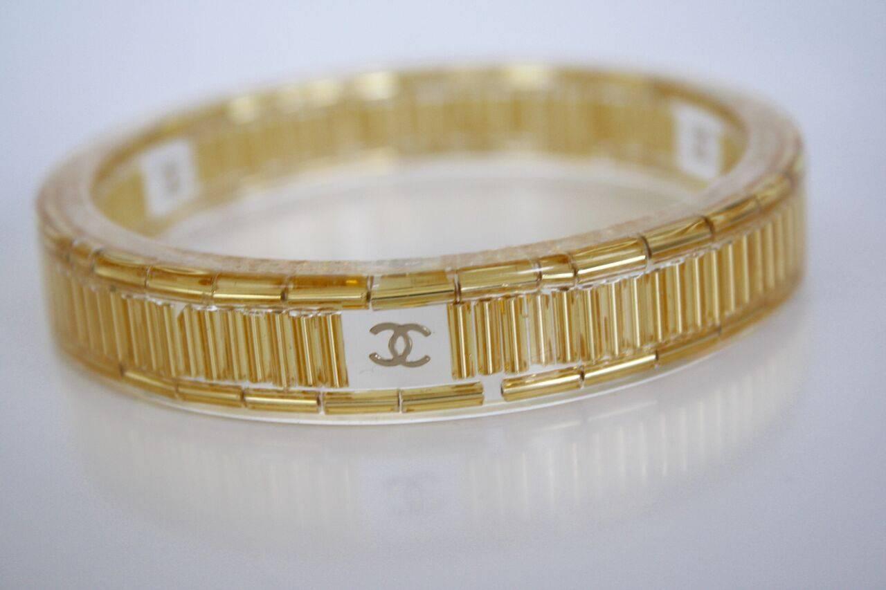 Chanel gold and clear resin bangle bracelet features 3 CC's around bangle and official Chanel stamp. In excellent condition, very minor wear. 


