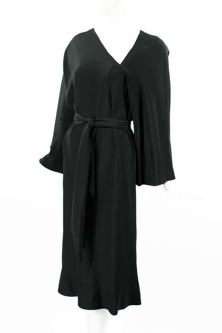 Halston 1970s Black Silk Dress with an asymmetrical neckline in front and back.
Wide kimono style sleeves. Comes with long silk belt that can also be worn as a scarf. In Excellent condition.
Fits size small to medium. 

Store
