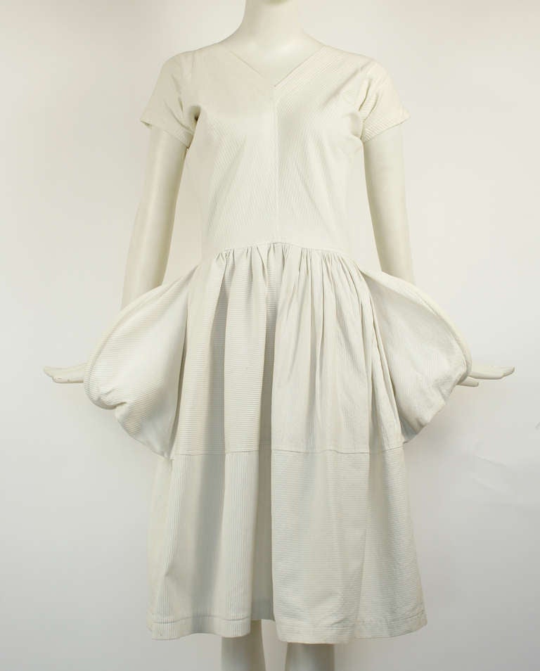 Comme des Garçons White Sculptural Dress. Zipper in back. Sculptural open detail on hips. V-neck. Full skirt.  Excellent Condition. 
Length: 42