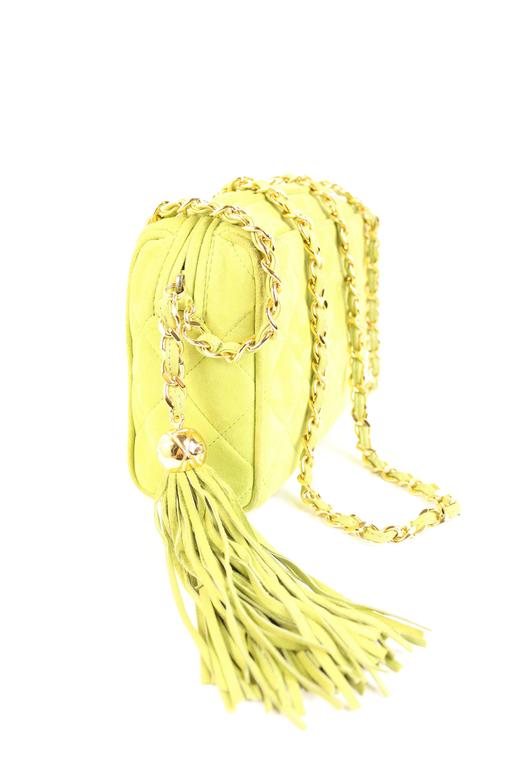 - Apple green quilted suede with a large frontal quilted Chanel CC logo from the 90s. 

- There is a long gold shoulder chain threaded with green suede. 

- A gold tipped tassel with strands of green suede for added flair. 

- The interior of the