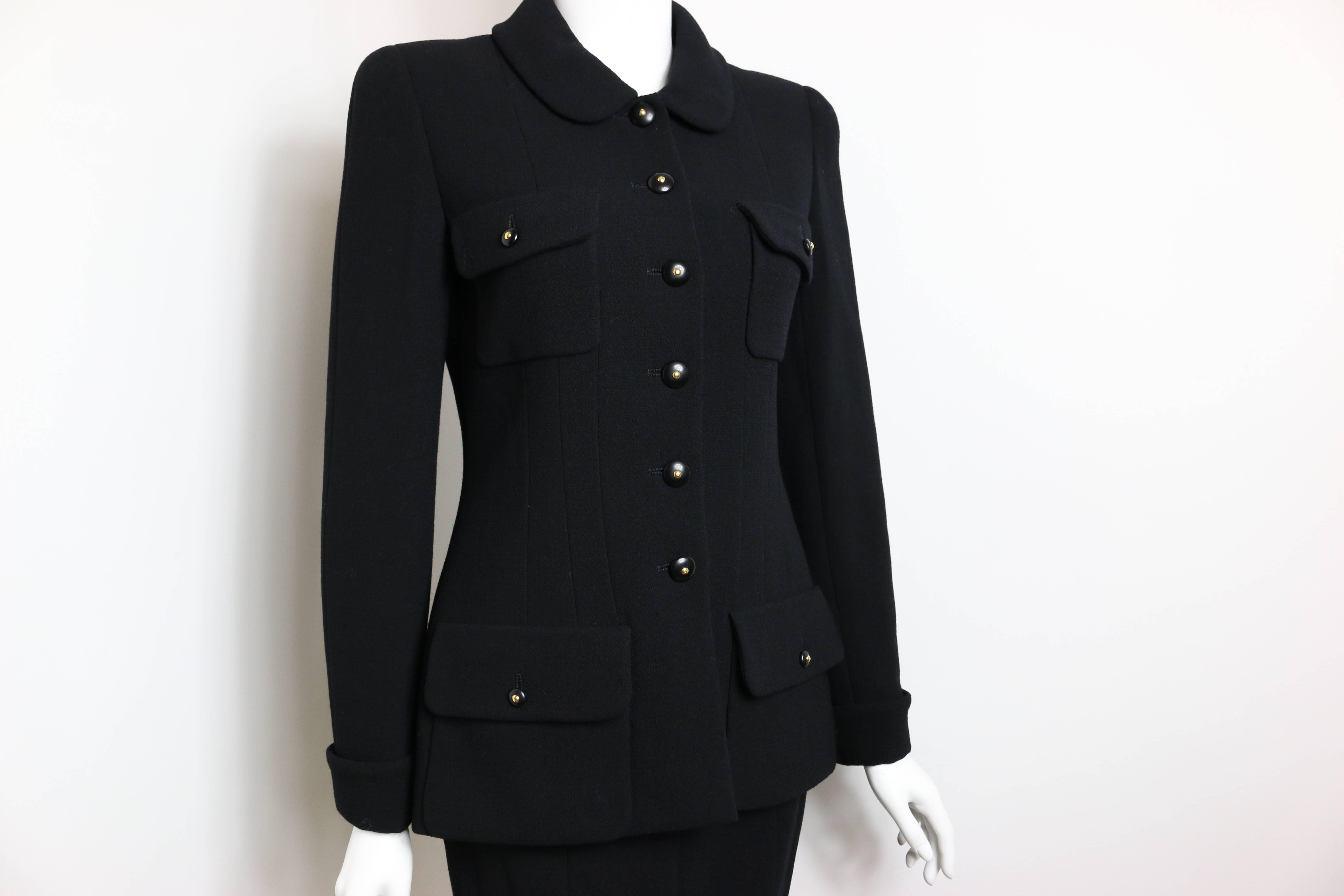- Chanel black boucle wool suit  from fall 1995 collection. 

- Military style inspired jacket. 

- Peter Pan style collar. 

- The jacket is featuring four front buttons pockets and six front center buttons. 

- Skirt has three buttons at