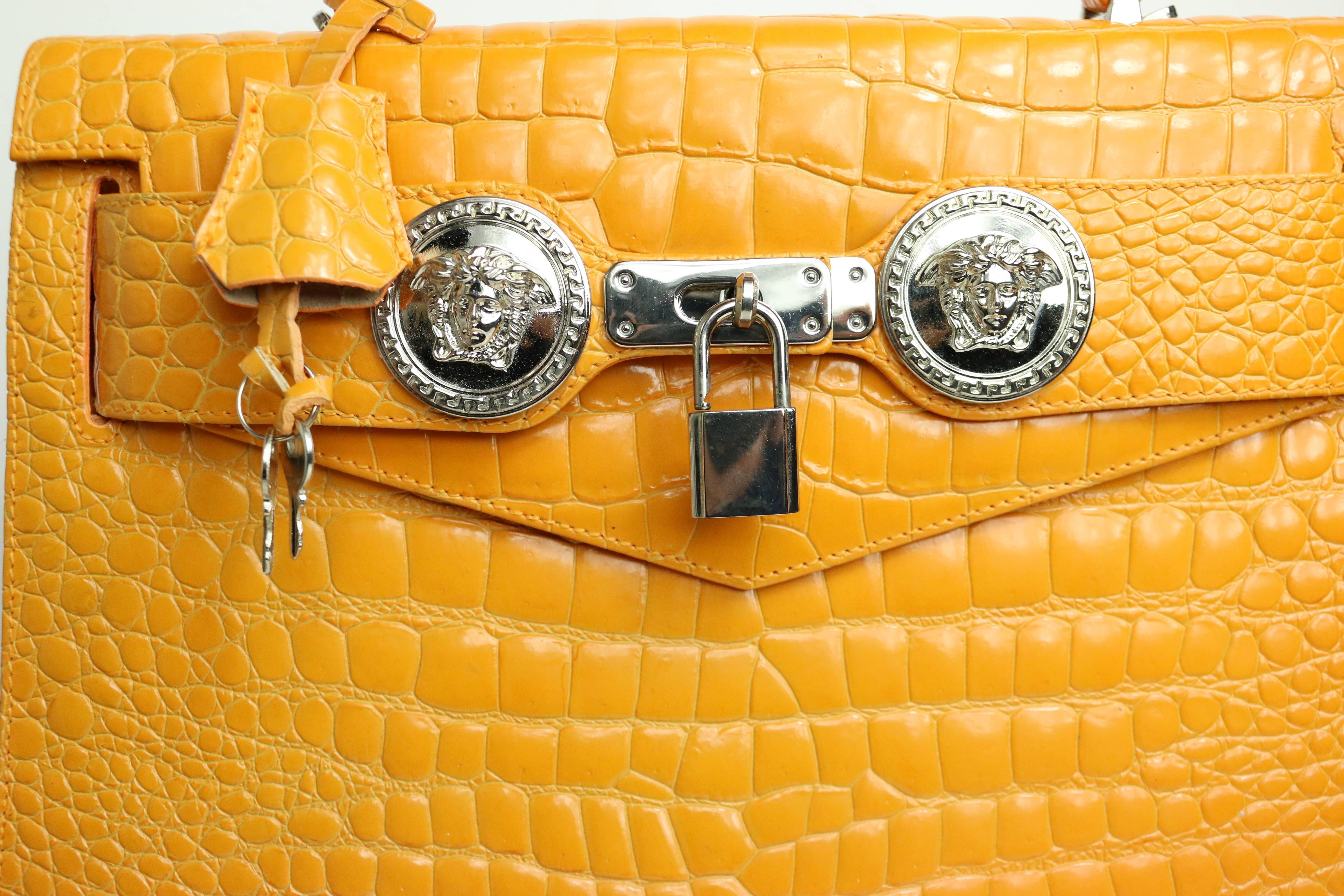 - Rare Vintage 90s Gianni Versace Orange croc embossed enamel leather kelly style with strap handbag, two signature Versace Medusa silver charms. 

- Height: 9.5in I Length: 12in I Width: 5.5 I Strap total length: 43in. 

- Please note this vintage