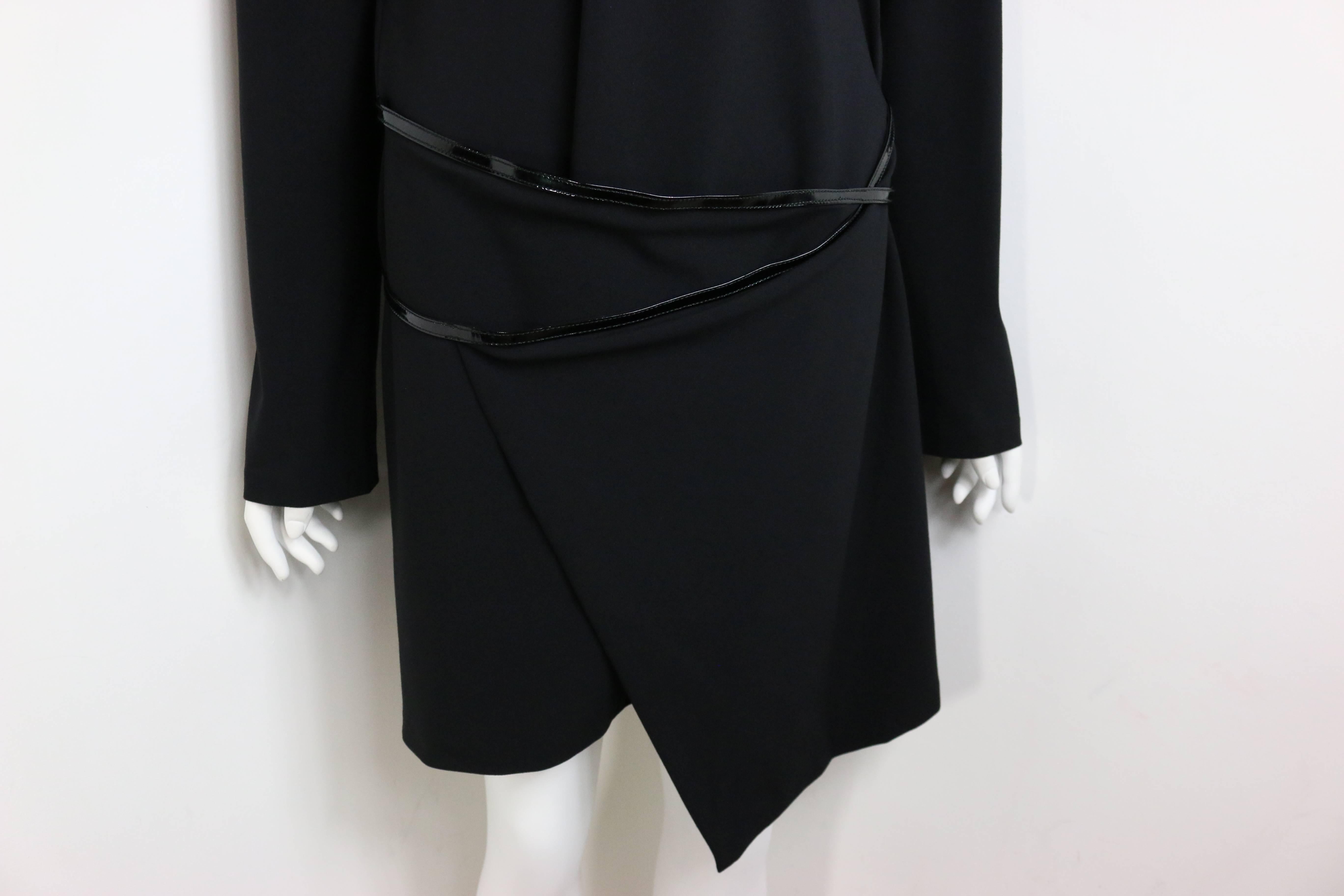 - Mini robe noire iconique des années 90 de la collection automne 1997 de Gucci by Tom Ford. 

- La robe est dotée d'une épaule structurée maintenue par des épaulettes, d'une ceinture en cuir verni à boucle métallique argentée Gucci 