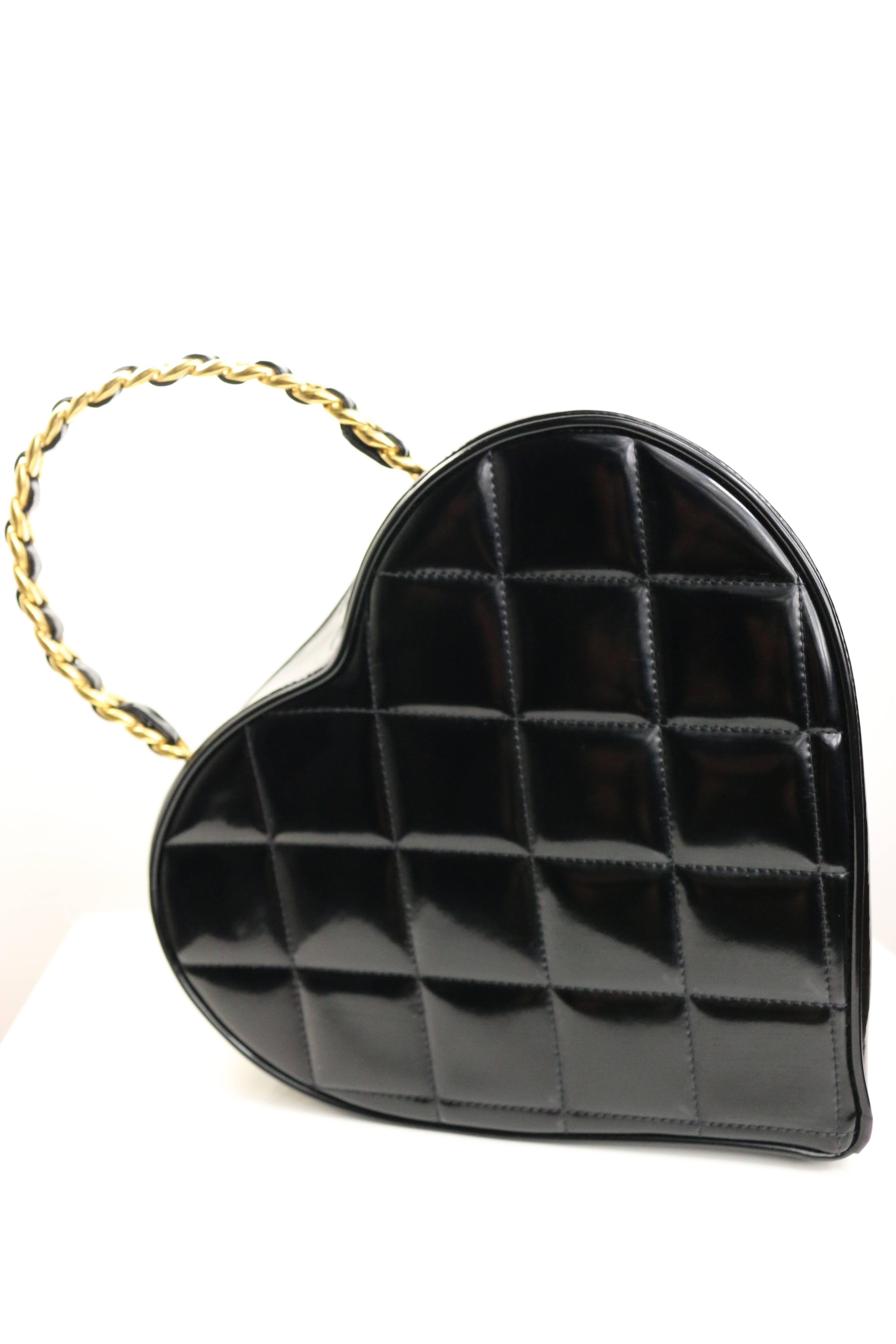 - Vintage Chanel black patent quilted leather heart-shaped vanity chain handbag from 1995 collection. 

- Featuring a woven gold-tone chain and interlocking "CC" logo in white across the front.

- Made in France. 

- Height: 9