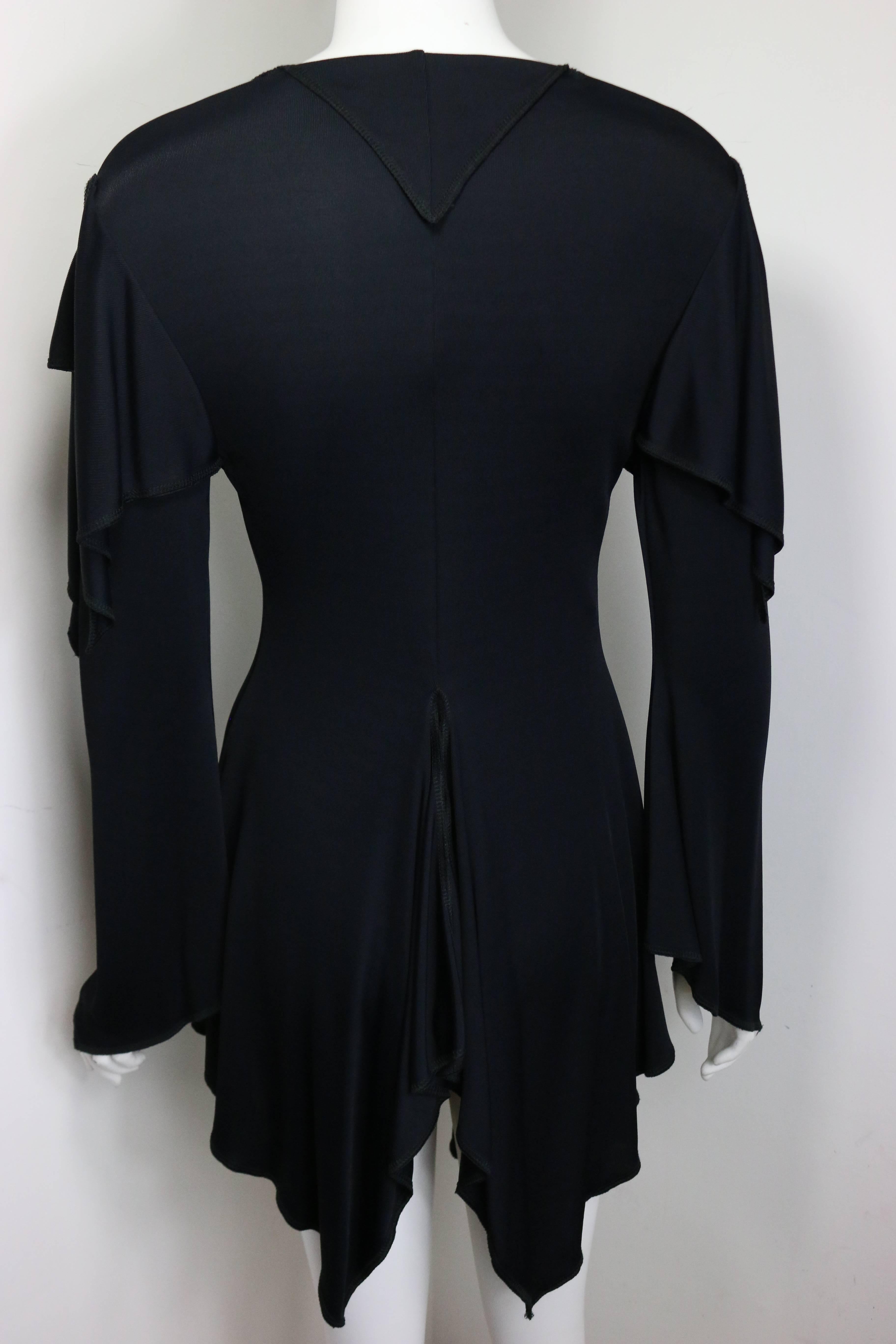 - Ce magnifique et unique cardigan mi-long noir vintage du début des années 90 de Moschino Couture se ferme par une lanière. Avec une couche supplémentaire sur les épaules. Il est renversé dans le dos et la coupe du gilet crée un effet plissé. De