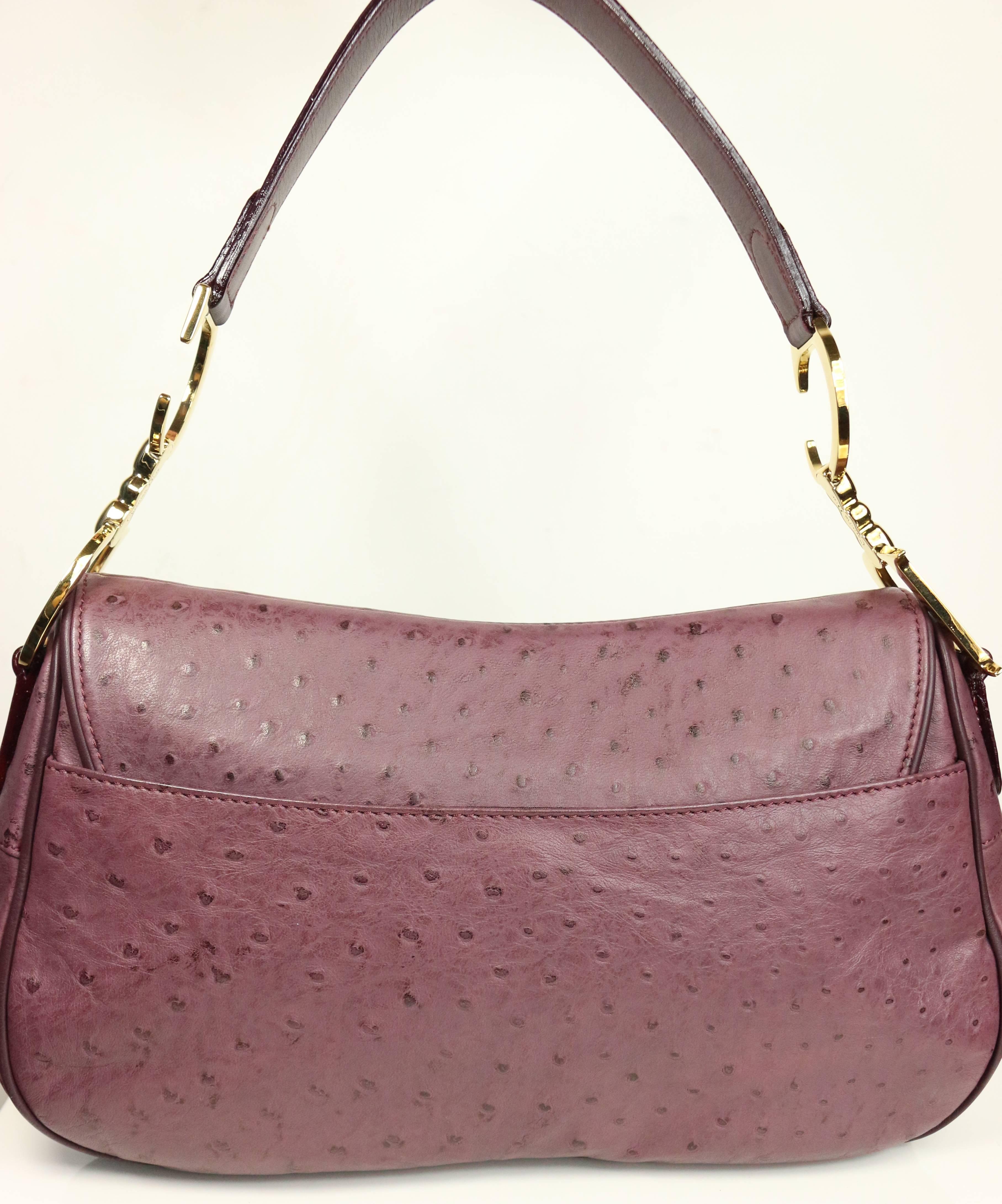 - Christian Dior aubergine double saddle handbag is finished in exotic Ostrich-skin with a front flap "CD" charm, an exterior back pocket, an interior zipper pocket and a beautiful crafted gold toned "CD" handle. This bag was a