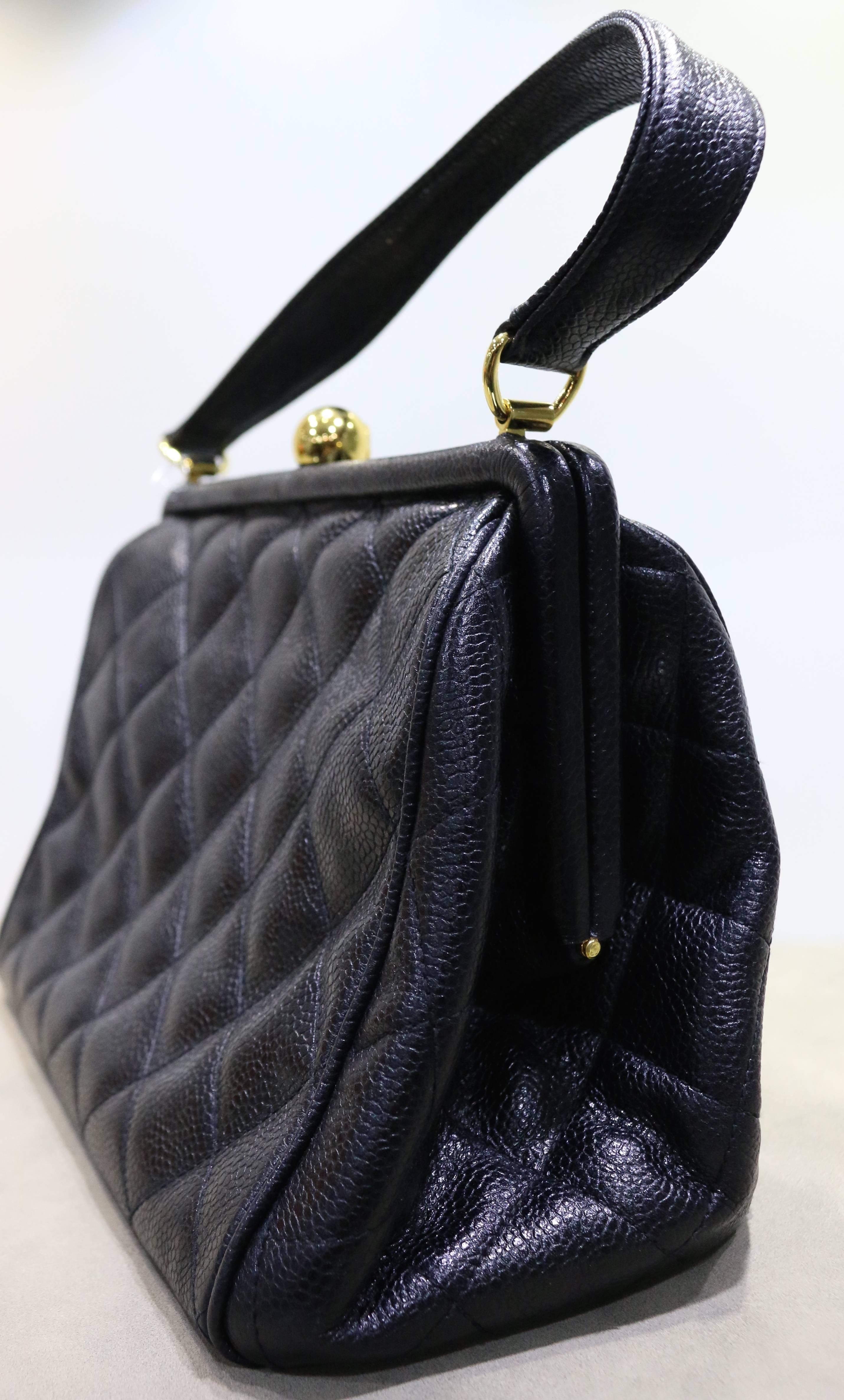 - Vintage 90s Chanel black quilted leather handbag.

- Hinges open with dome shape CC clasp. 

- Embroidered "CC" logo on bottom. 

- Height : 7 inches. Handle: 6 inches. Length: 8.8 inches. Width: 4.35 inches. 

- Includes: Authenticity