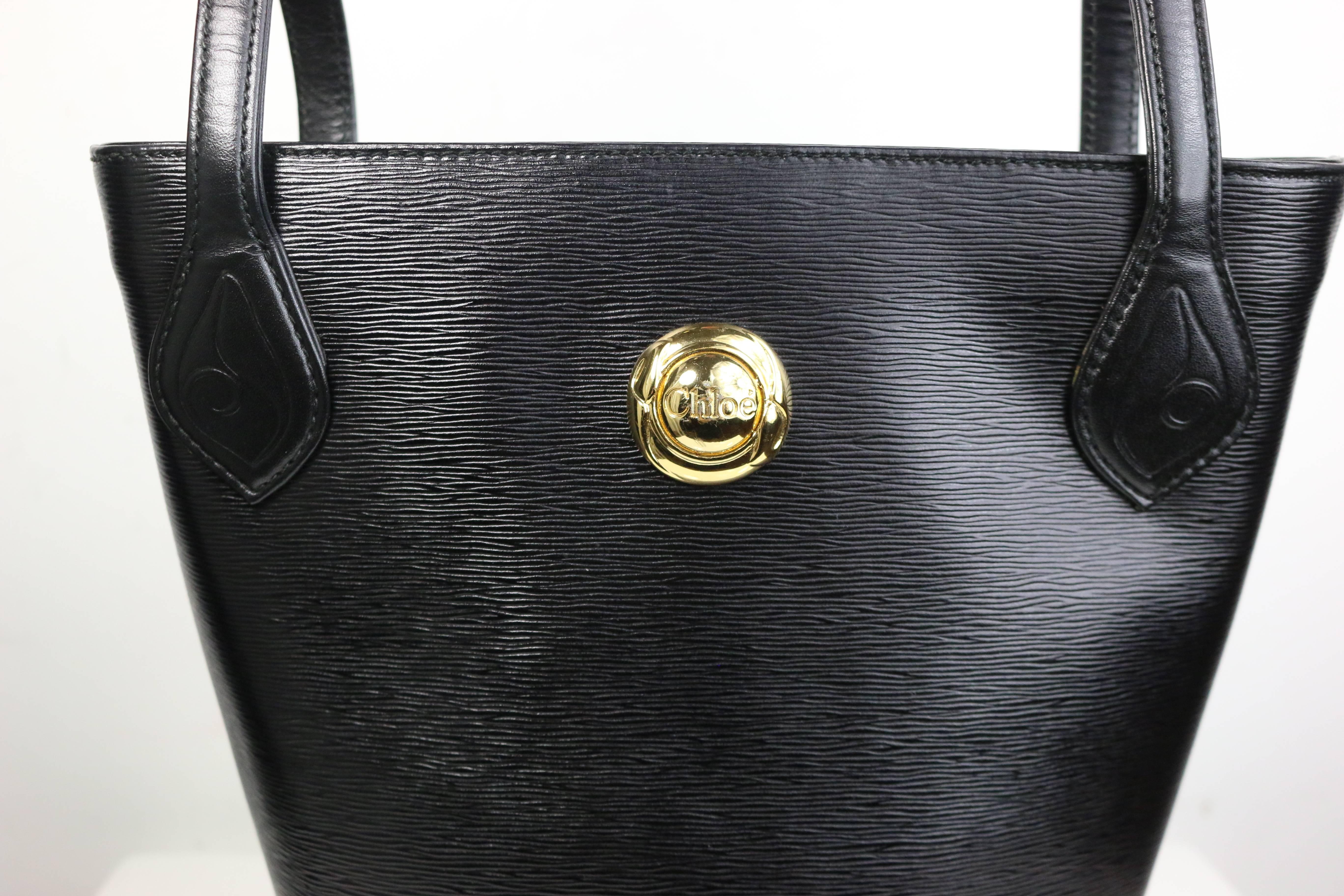- Vintage 90s Chloe black leather bucket bag with adjustable leather strap. This bag can be worn in shoulders. Featuring an embedded gold toned hardware "Chloe" logo in front, a gold zipper fastening, and the interior has one zipper pocket