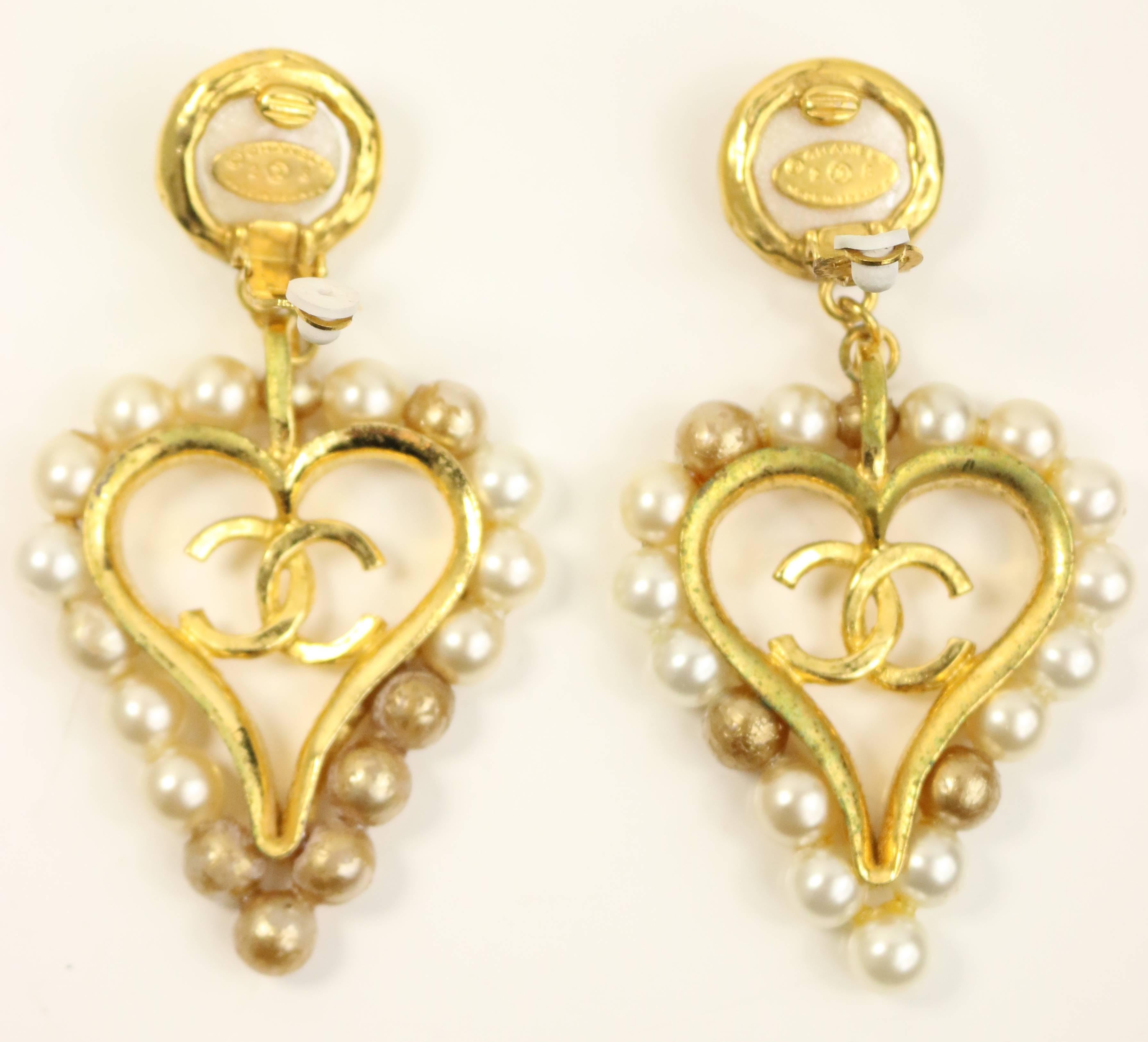 - Vintage 90s Chanel faux pearl gold toned setting with drop heart shaped clip on earrings. Chic, elegant and playful elements all in one! Some of the pearls have changed colour but in excellent condition. 

- Featuring gold toned setting