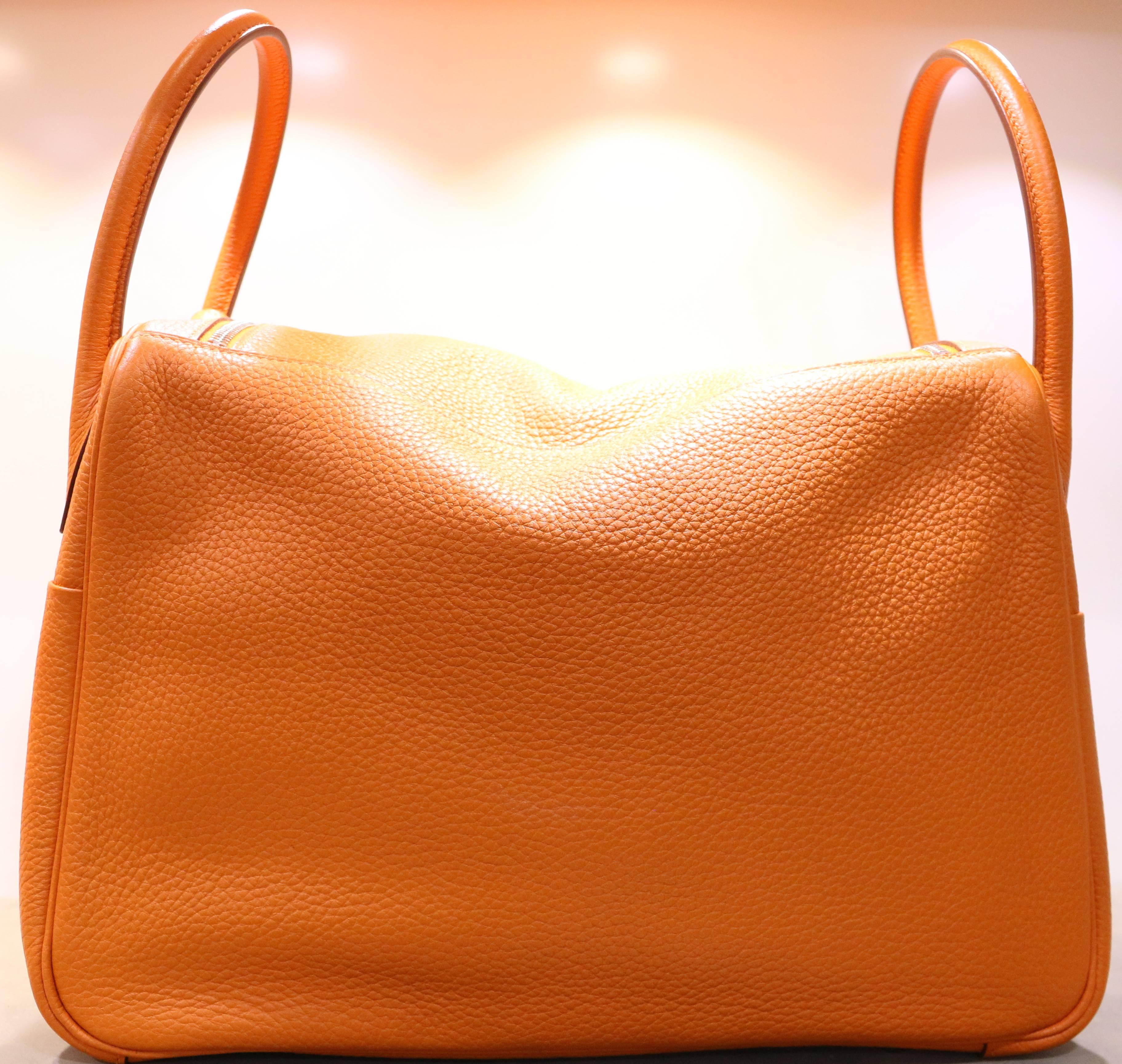 - This super elegant and chic Hermes Lindy in orange colour is crafted of  Taurillon Clemence leather. Featuring an unique looping shoulder strap and a frontal flap with a strap and palladium silver turn lock mechanism. Super spacious leather