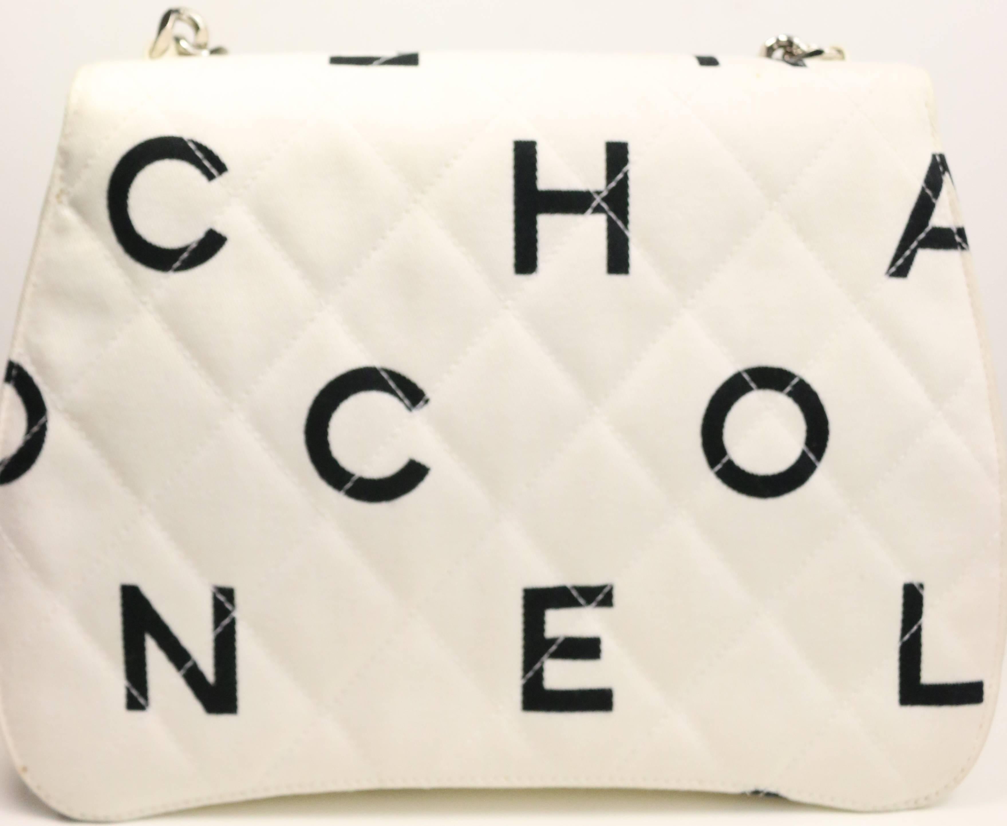 - Vintage 90s Chanel white quilted with black logo print canvas flap bag and accentuated with a silver hardware strap from Chanel circa 1996- 1997. Featuring leather interior zipper and patch pockets. 

- Made in France. 

- Includes: Authenticity