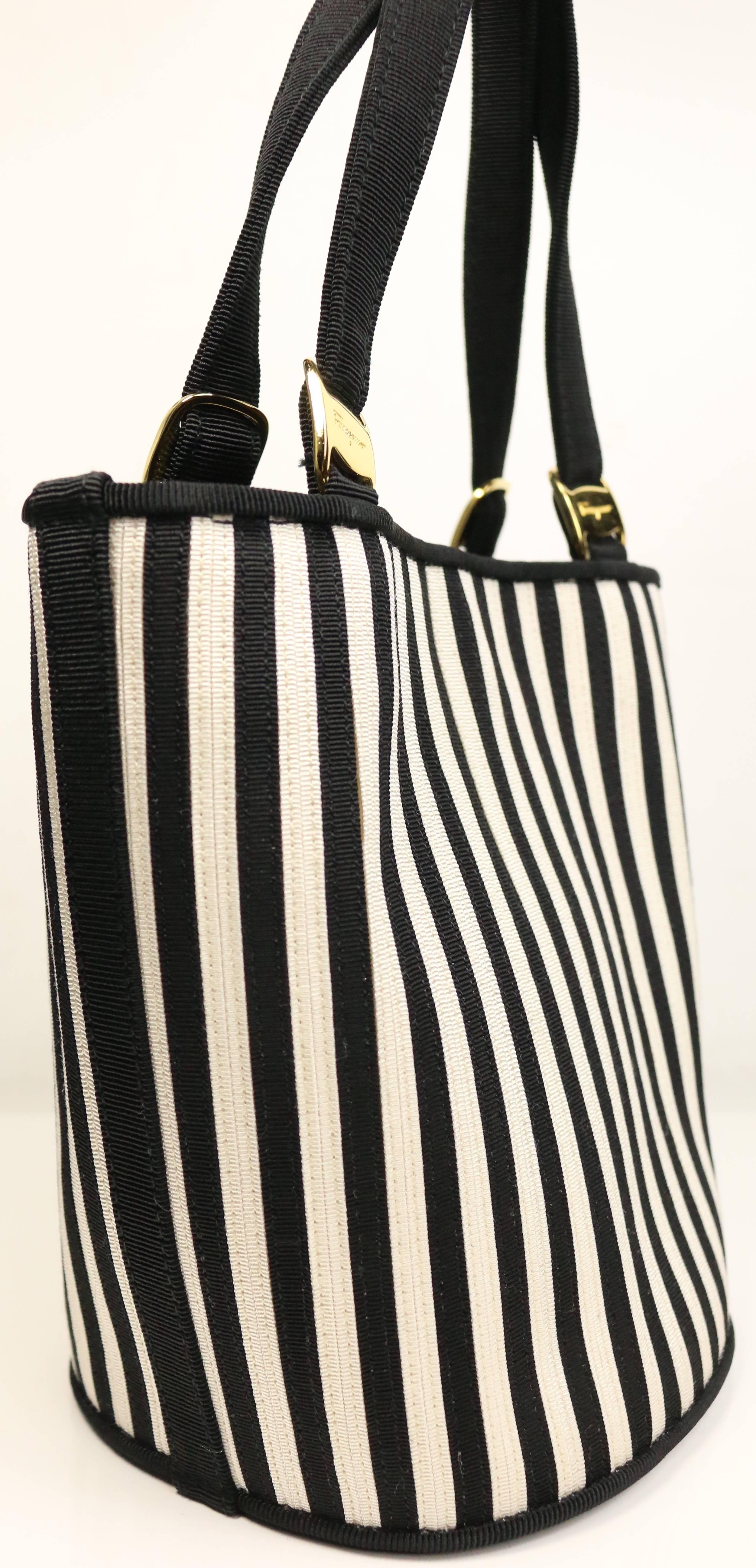 - This vintage 80s Salvatore Ferragamo black and white strap bucket handbag with detachable strap is made in rayon and cotton. Featuring a gold hardware hook closure, a strap that can be adjusted and interior zipper pocket. Versatile, classic and