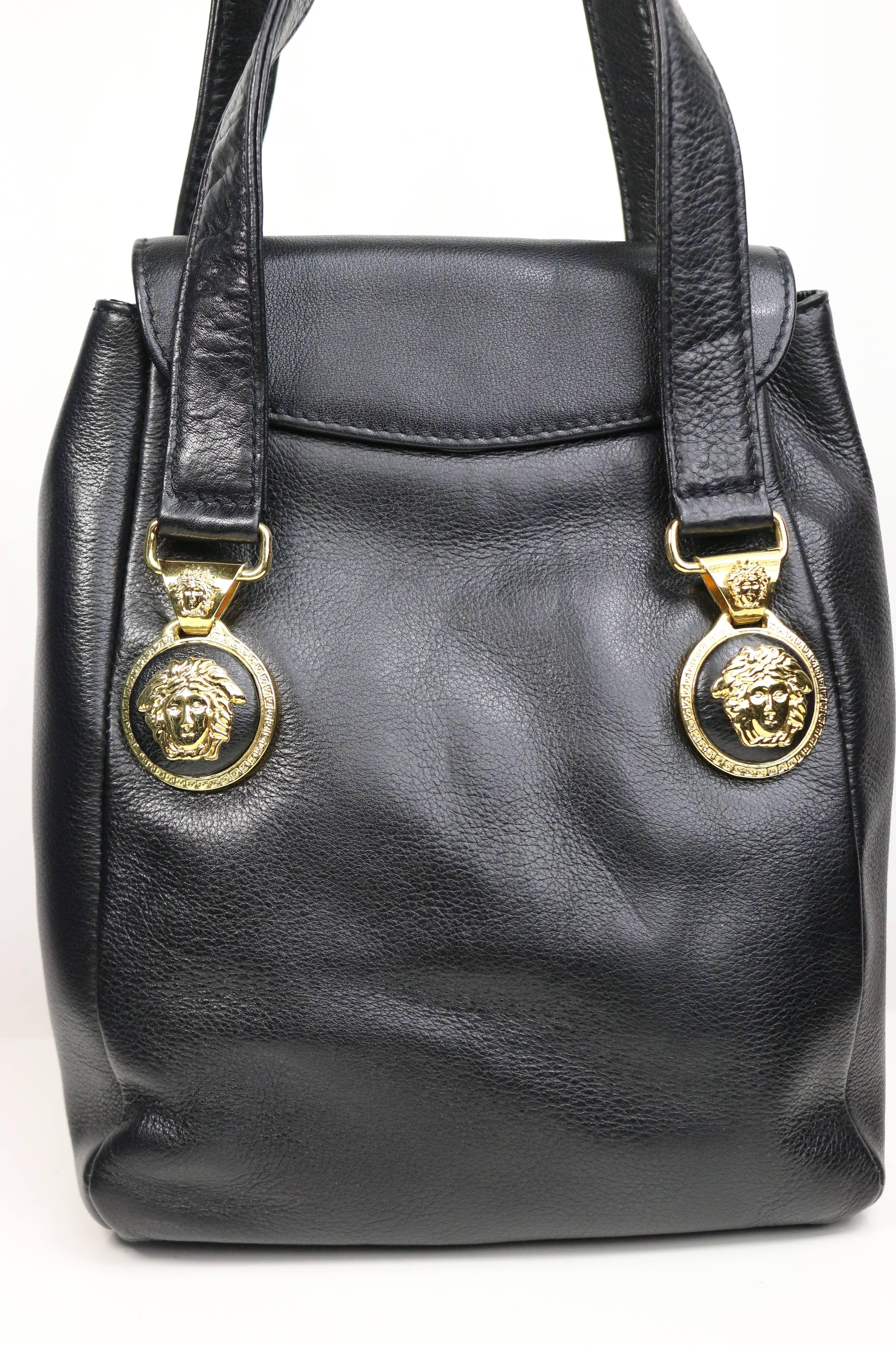 - Vintage 90s Gianni Versace black leather medusa mini handbag. Featuring four front and back signature black leather gold Medusa buckles embedded for the straps handle . Also, a small exterior pocket and interior zipper pocket. This cute mini size