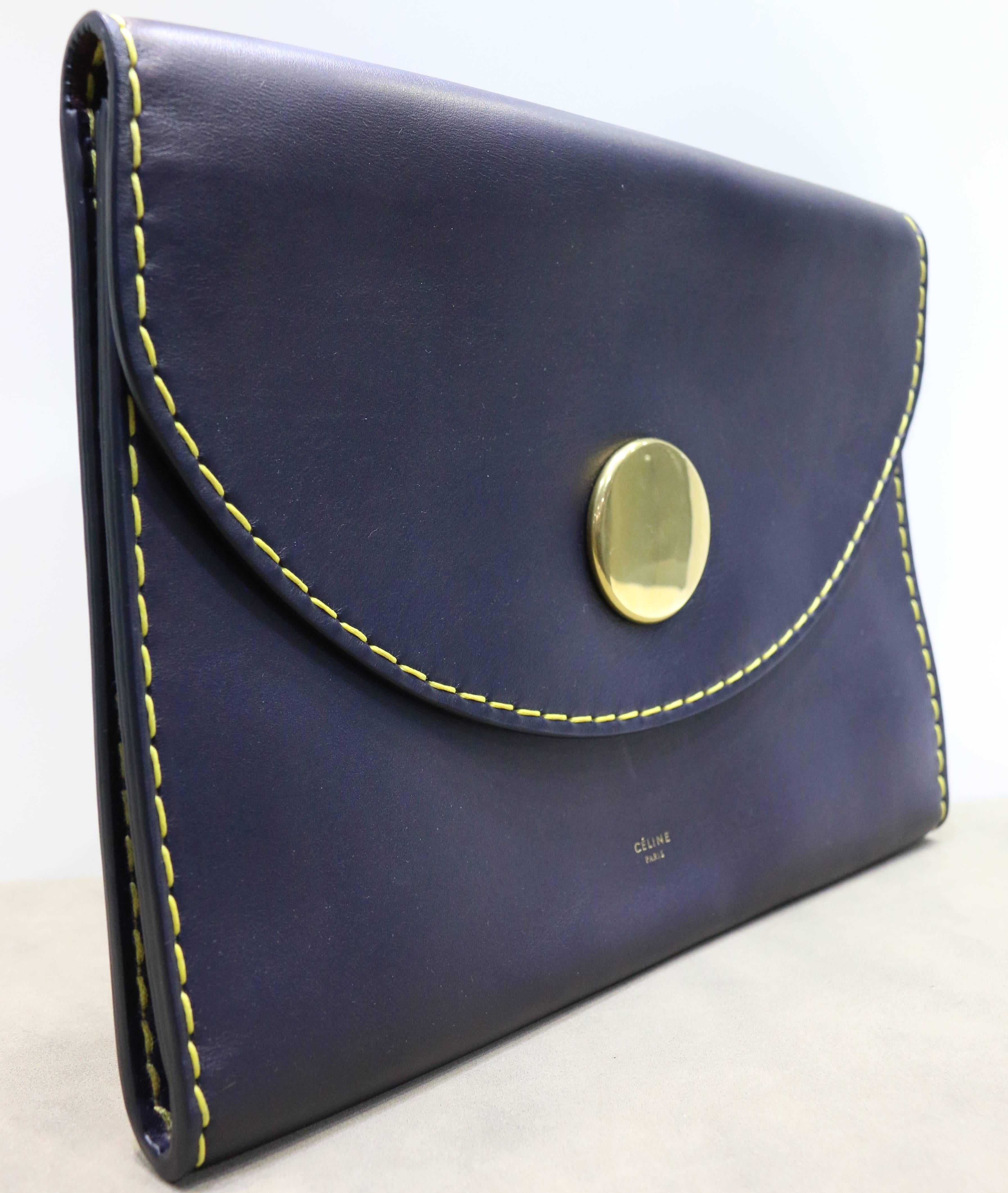 - Celine navy with yellow stitched calfskin leather flap clutch with contrast big gold hardware button closure. This clutch is light and easy to carry around especially for party. Red leather interior is spacious and have two compartments. You can