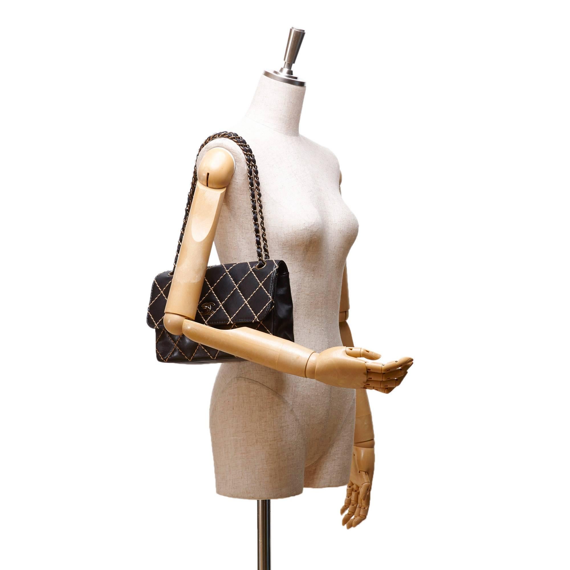 - Chanel black quilted beige wild stitch flap bag features a lambskin leather body, exterior back slip pocket, front flap with silver interlocking Cs and twist lock closure,closure, gold-tone hardware, chain shoulder strap, an open top, and an
