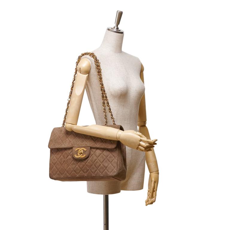 The vintage Chanel bag is made of quilted brown suede. A long golden chain  handle and a flap closure in the form of a brand logo. Bag size 19x12x6 cm,  handle length