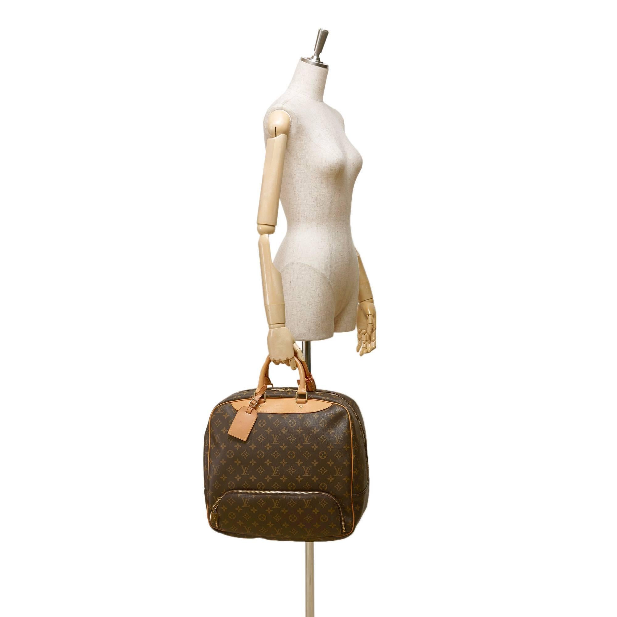 - The brown and tan Louis Vuitton Evasion Boston luggage features a coated monogram canvas body, brass hardware, tan vacate leather trim, dual rolled leather top handles, an exterior zip pocket, a top zip closure, an interior slip pocket and beige