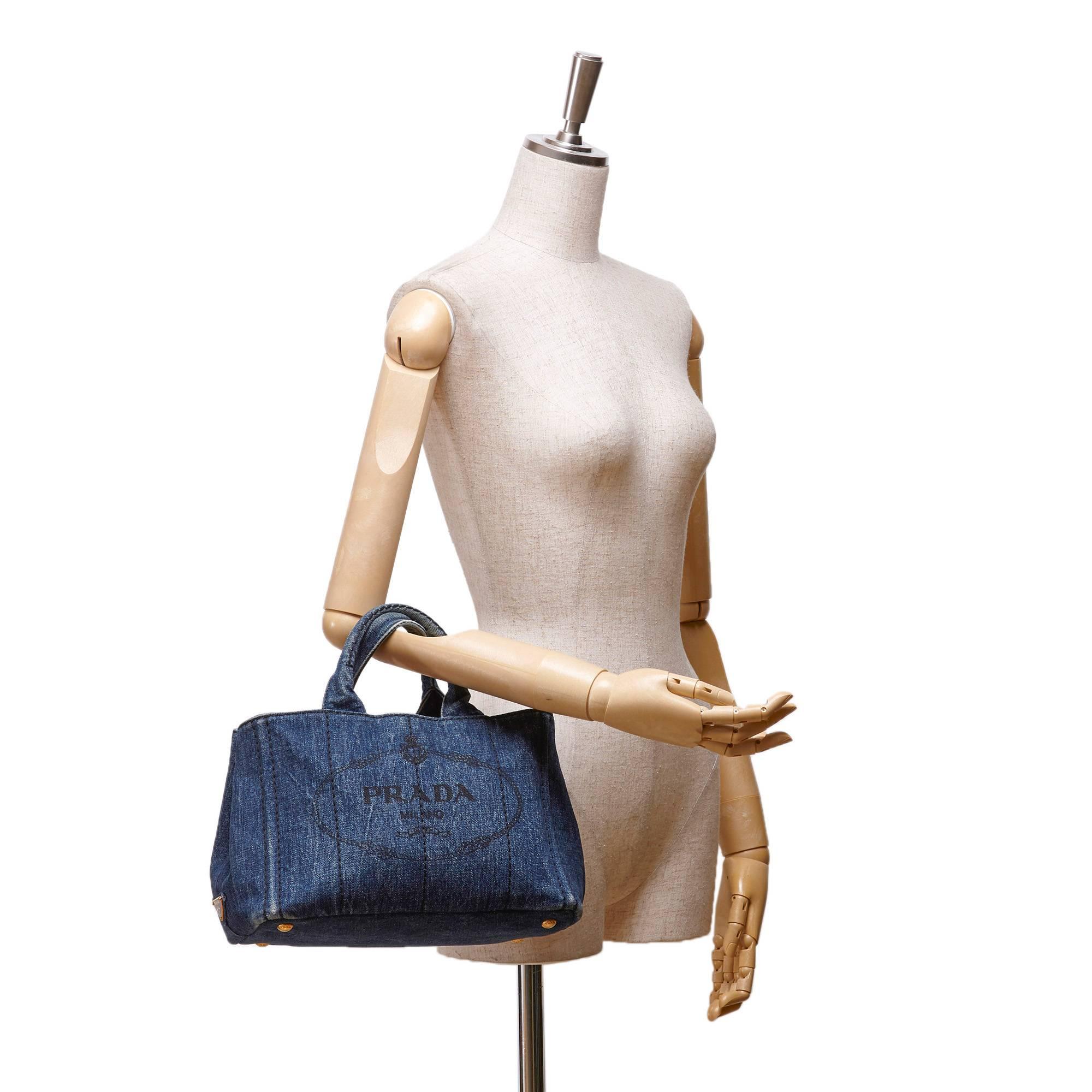 - This Prada tote bag features a denim body, rolled handles, an open top, and interior zip pockets. A chic casual bag for summer get away! 

- Made in Italy. 

- Size: 29cm x 20cm x 11cm. Shoulder Drop: 15cm. Hand Drop: 11cm. 

- Condition: Edge is