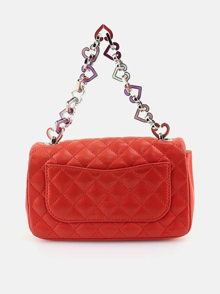 - Chanel orange quilted lambskin heart charm chain mini flap handbag. Featuring a silver hardware "CC" interlock closure. A silver satin "Chanel" interior with a slip pocket. 

- Made in France.

- Length: 5.5 inches. Height: