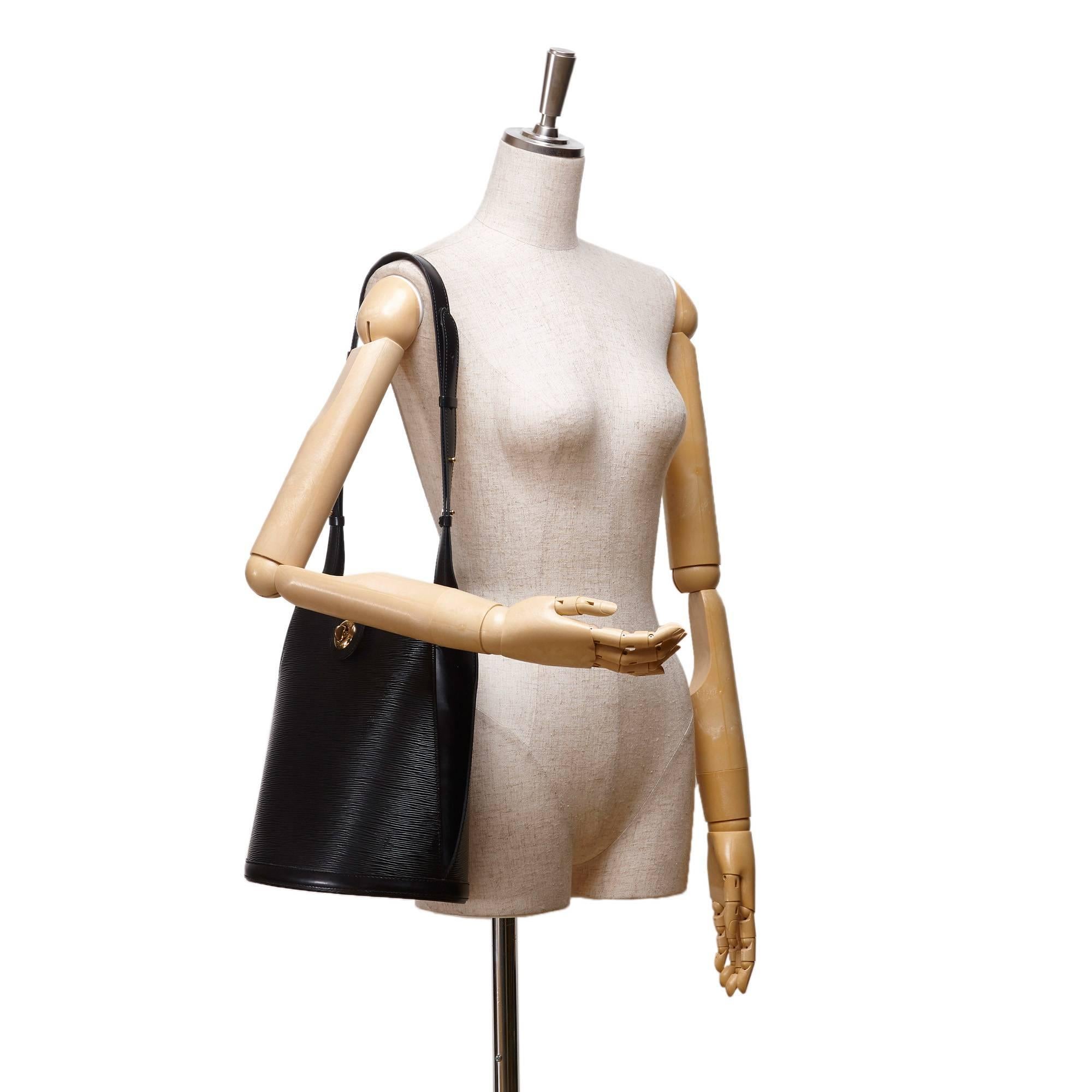 - This Vintage 1997 Louis Vuitton Cluny bucket shoulder bag features an black epi leather body, an adjustable shoulder strap, a top strap with a twist lock closure, and an interior slip pocket.

- Made in France. 

- Size: 26cm x 30cm x 17cm.