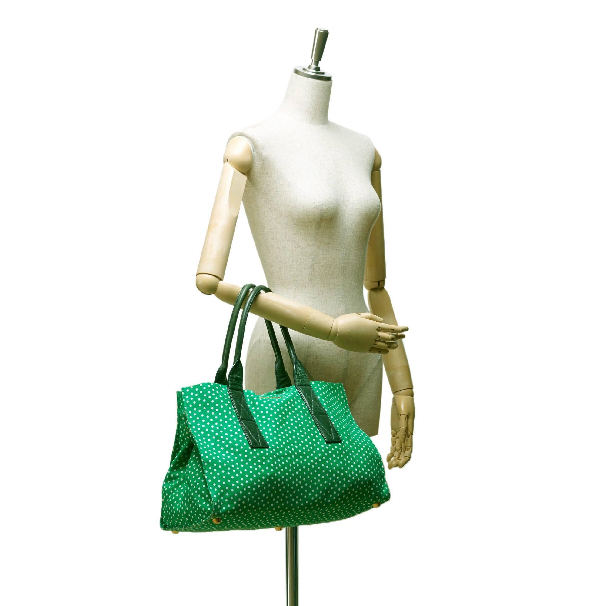 - This Mui Mui white polka dot tote bag features a green canvas body, rolled leather straps, open top with button clasp closure, and interior zip and slip pocket. A very cute bag of Mui Mui! 

- Made in Italy. 

- Size: 39cm x 26cm x 21cm. Shoulder