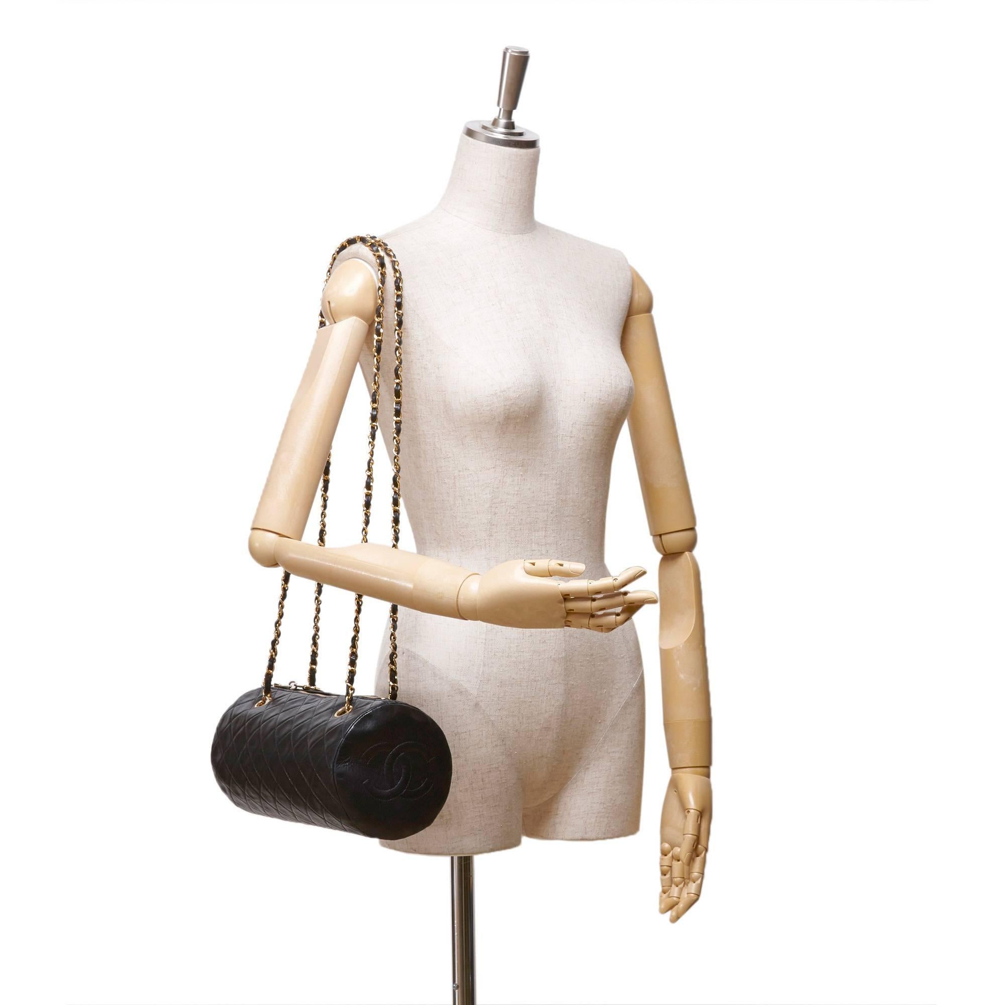 - Este bolso de hombro cilíndrico de Chanel presenta un cuerpo de piel de cordero acolchada negra, cadenas doradas, bolsillo interior con cremallera y cierre superior con cremallera. 

- Fabricado en Francia. 

- Tamaño: 14 cm x 26 cm x 5 cm. Caída
