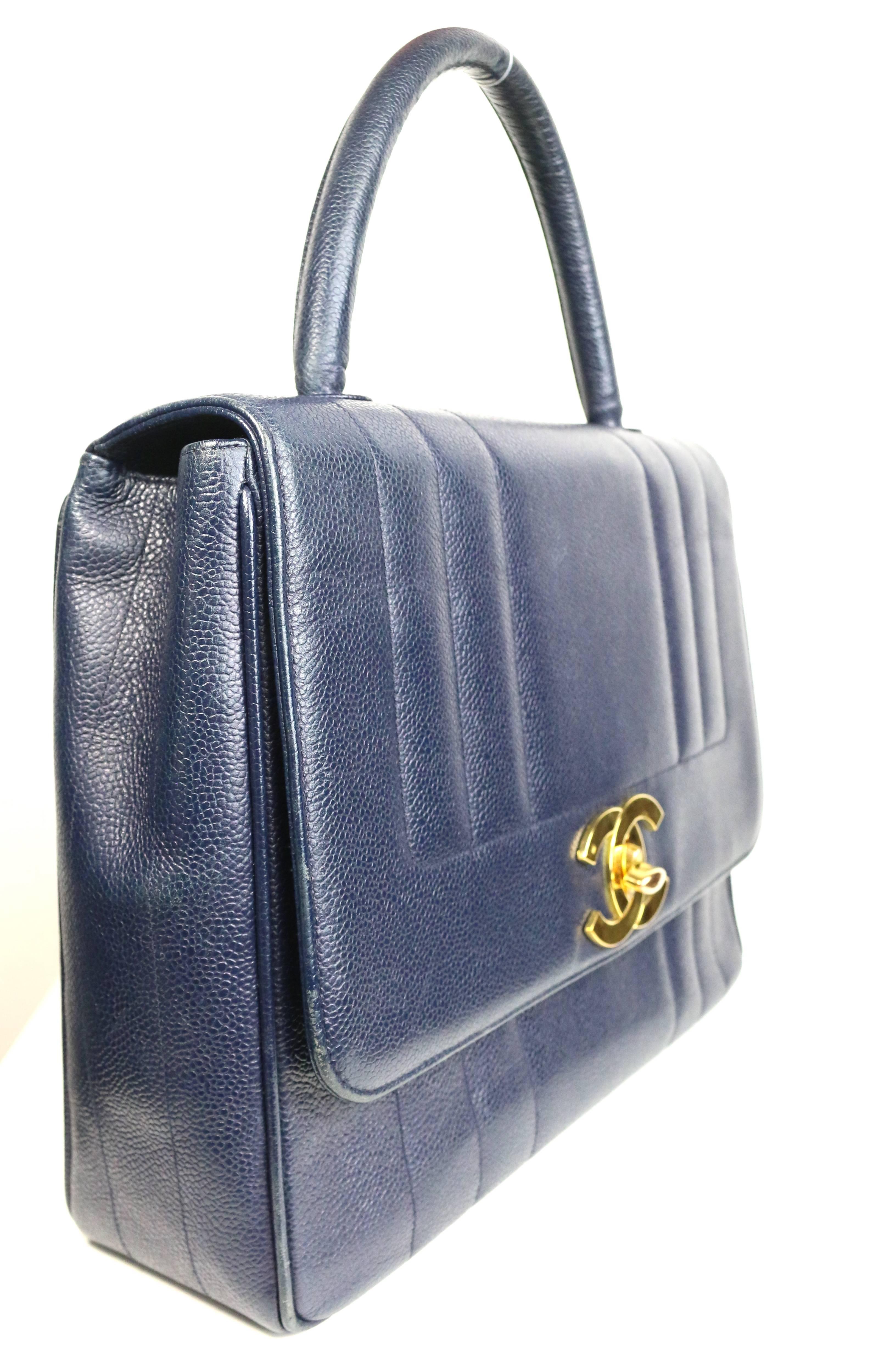 - Vintage 90s Chanel navy blue caviar leather flap handbag. 

- Classic gold toned "CC" Interlock closure. 

- Exterior Pocket. 

- One Interior zip pocket and one open pocket. 

- Length: 12 inches. Height: 9 inches. Width: 3.5 inches.