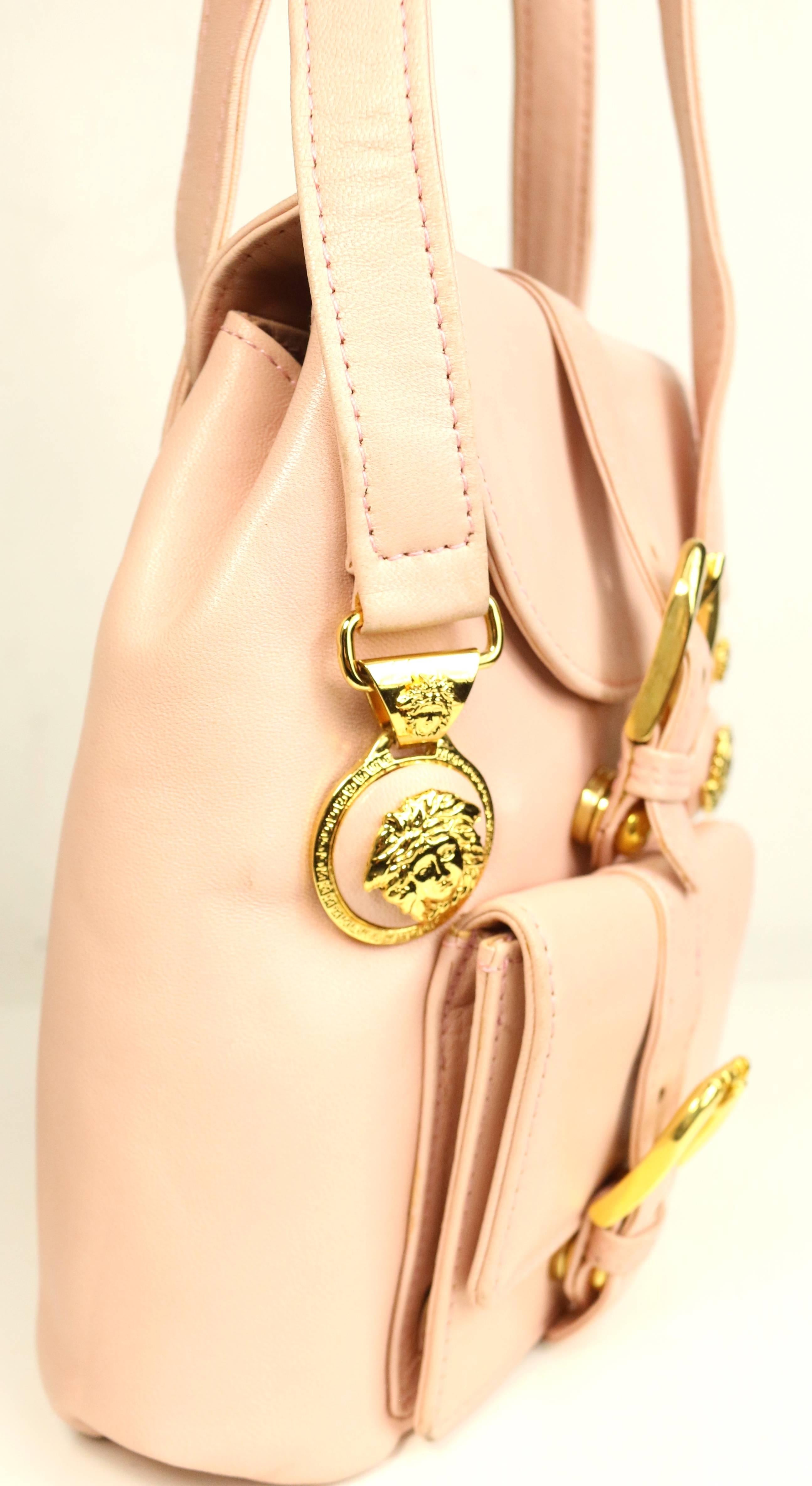 - Vintage 90s Gianni Versace pink leather goldmedusa mini handbag. 

- Four front and back iconic pink leather gold Medusa embedded for the straps handle . 

- Two front gold buckle with snap button closure. 

- one exterior flap pocket and one
