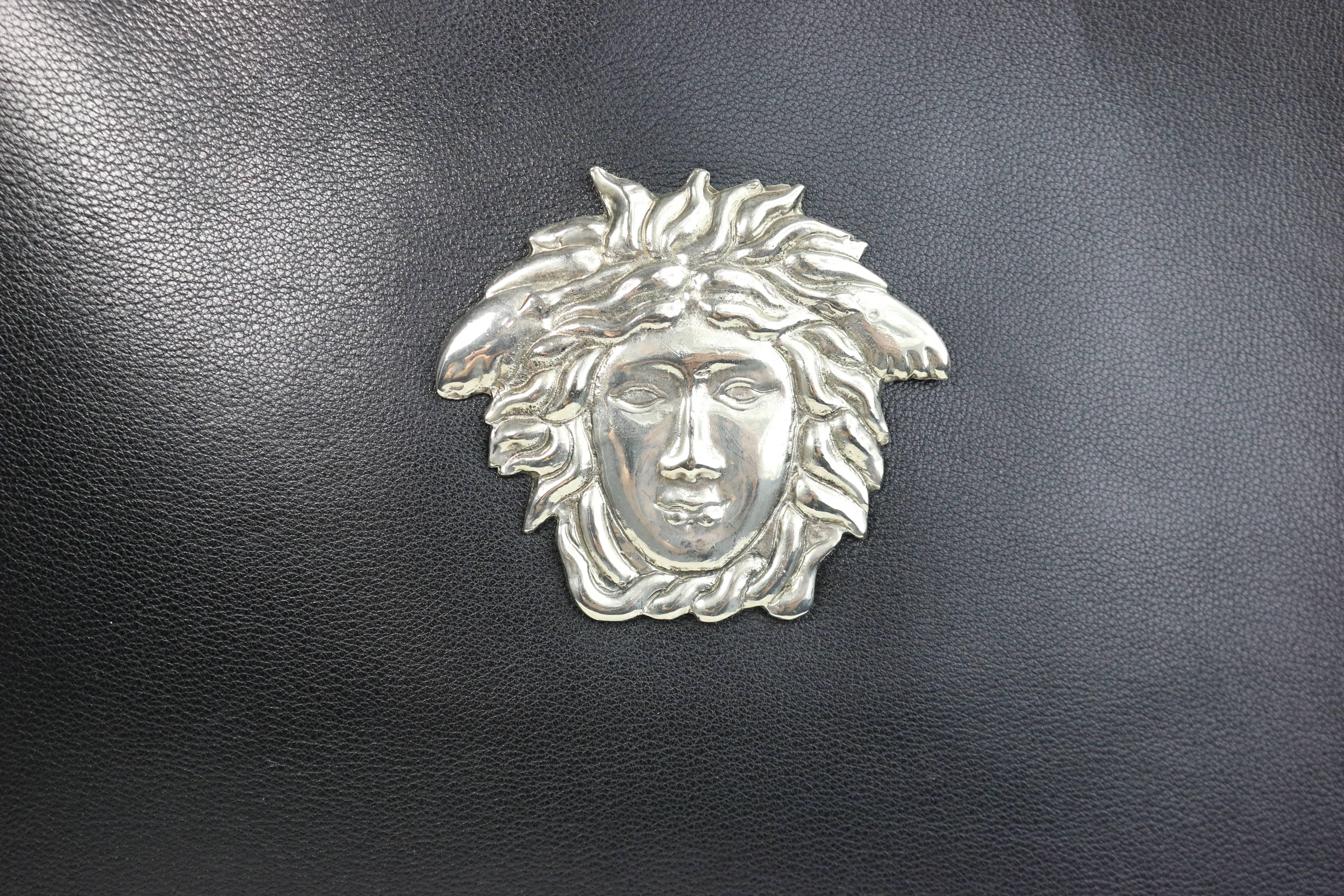 - Vintage 90s Gianni Versace black leather embedded silver Medusa handbag. 

- Silver toned metal Medusa double handle. 

- Silver toned Medusa zip closure. 

- Interior zip pocket. 

- Length: 10 inches. Height: 8.5 inches. Width: 3 inches. Hand