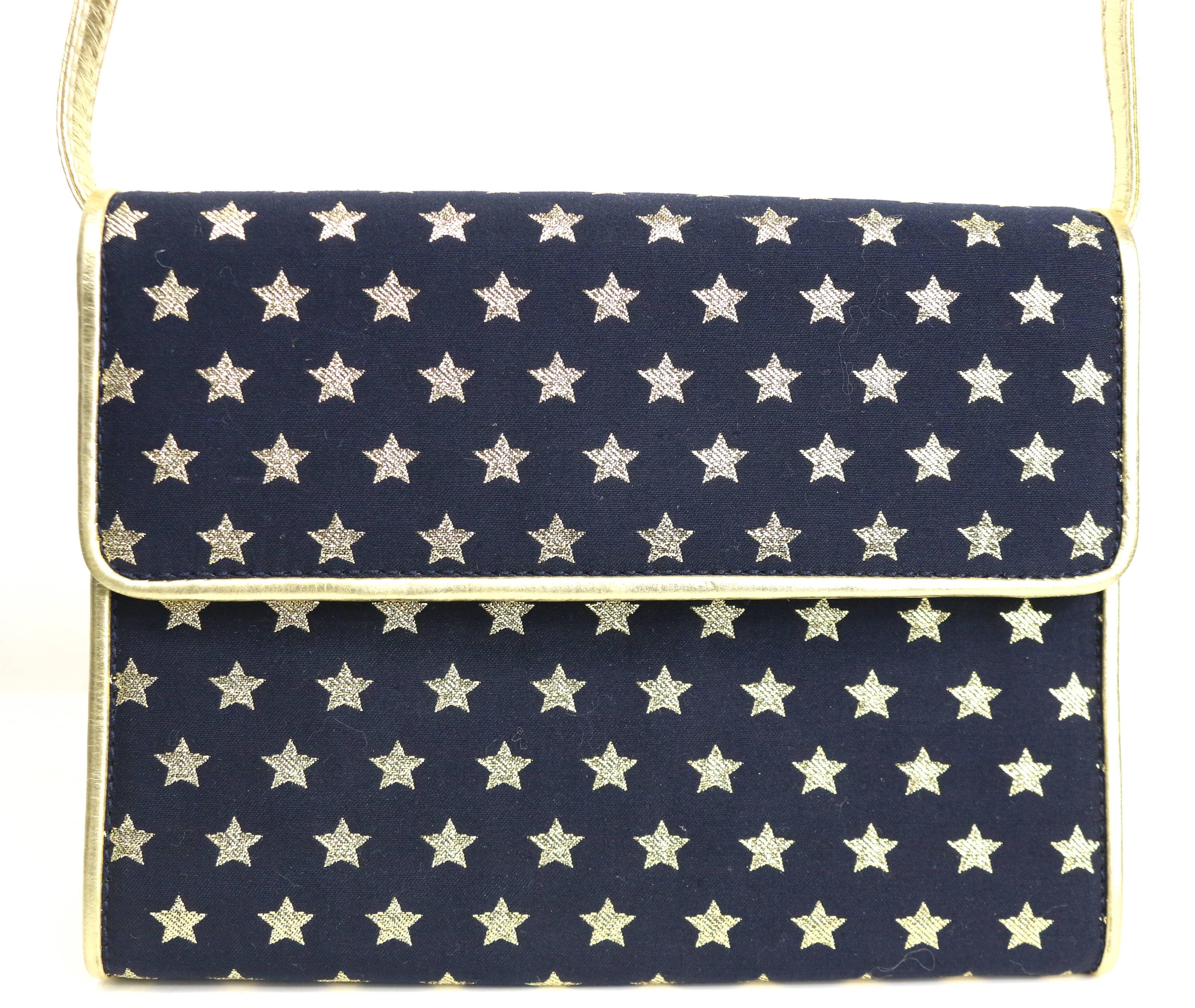 - Vintage 80s Escada dark navy with gold metallic stars shoulder bag. 

- Featuring gold metallic leather piping trim. 

- Flap with snap button closure. 

- Detachable gold metallic shoulder strap. 

- Interior zip closure. 

- Length: 7 inches.