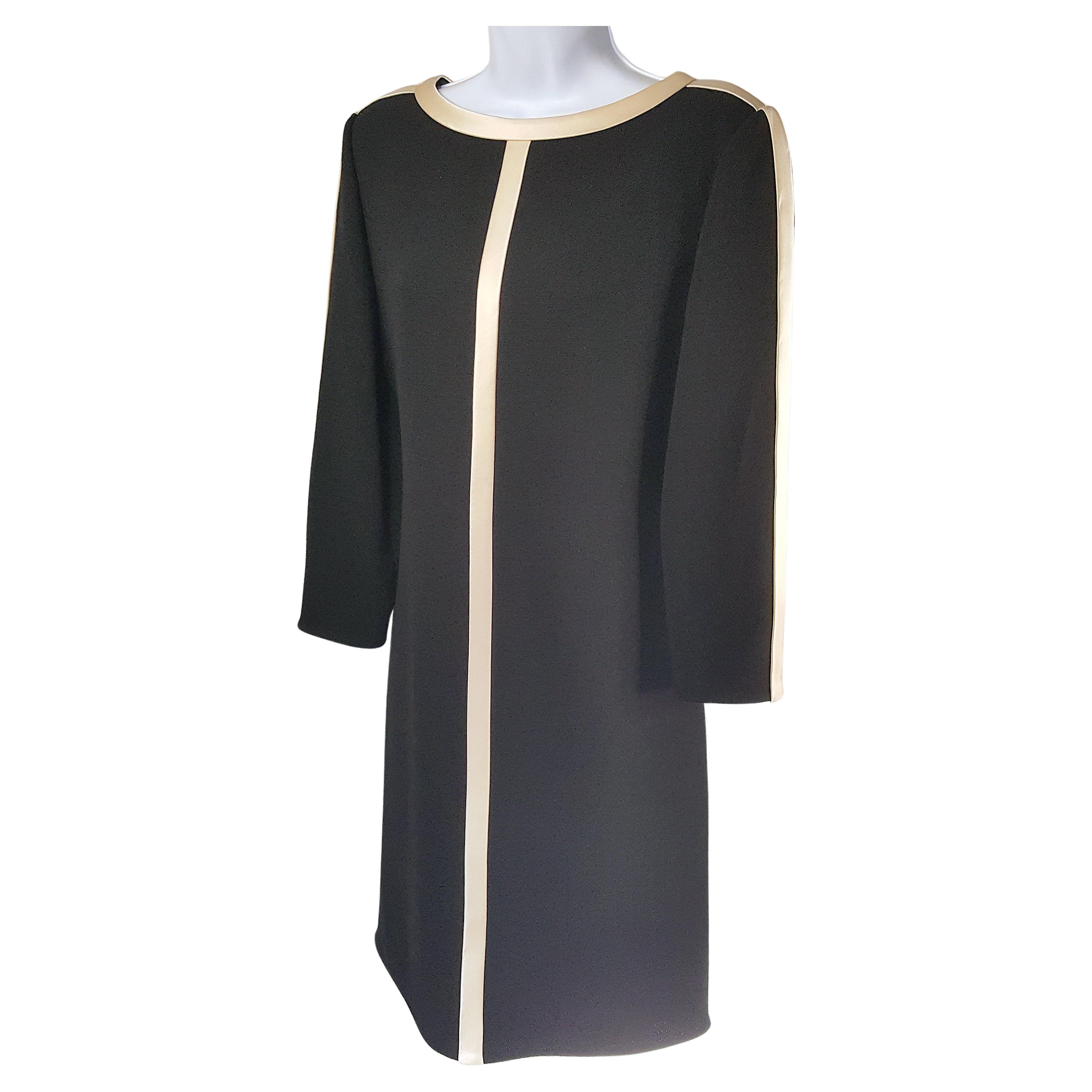 Around 1970 when Bill Blass introduced his eponymous brand after becoming a leading couture fashion designer among New York City society, he created this sleek tuxedo-like ecru-satin-trimmed long-sleeve black wool crepe shift dress. The thick shiny