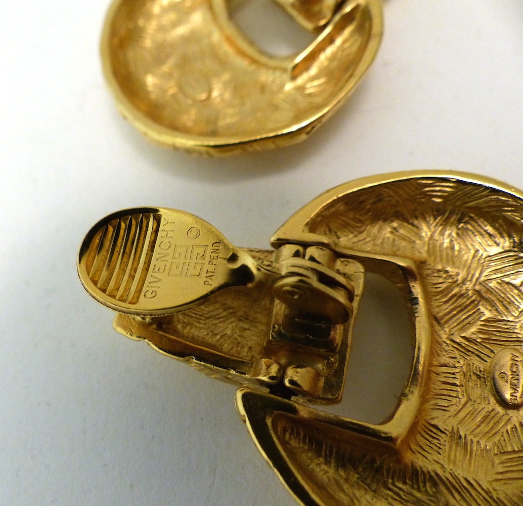 These vintage signed Givenchy earrings features a heavily etched gold-tone setting.  These clip earrings measure 1 7/8” x 1 ½”, are signed ‘Givenchy’ and are in excellent condition.