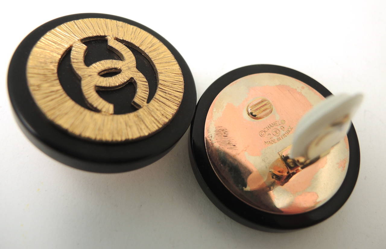 These vintage signed Chanel earrings feature the famous CC logo in a ridged gold-tone on a black resin disc.  These clip earrings measure 1 ½” in diameter, are signed ‘Chanel 29 Made in France’, and are in excellent condition.