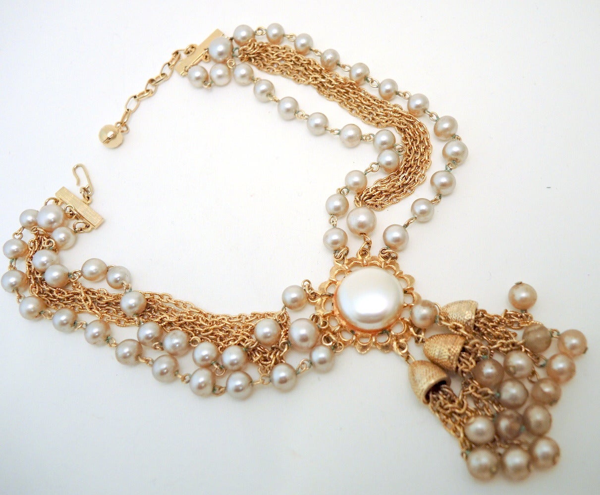 This vintage necklace features faux pearls in a gold-tone setting.  The necklace has two strands of faux pearls and 5 strands of link chain.    In excellent condition, this necklace measures 16 1/2” with a hook closure; the pendant is 3” x 1 1/4”