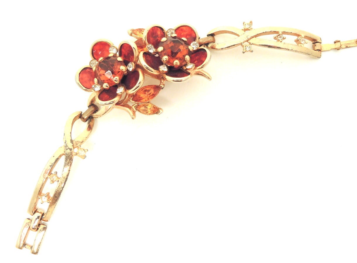 This vintage 1940s retro bracelet features a floral design with topaz, citrine and clear rhinestones in a gold-tone setting.  In excellent condition, this bracelet measures 6” with a fold-over closure; the centerpiece is 1 ¾” x 1 1/8” wide.