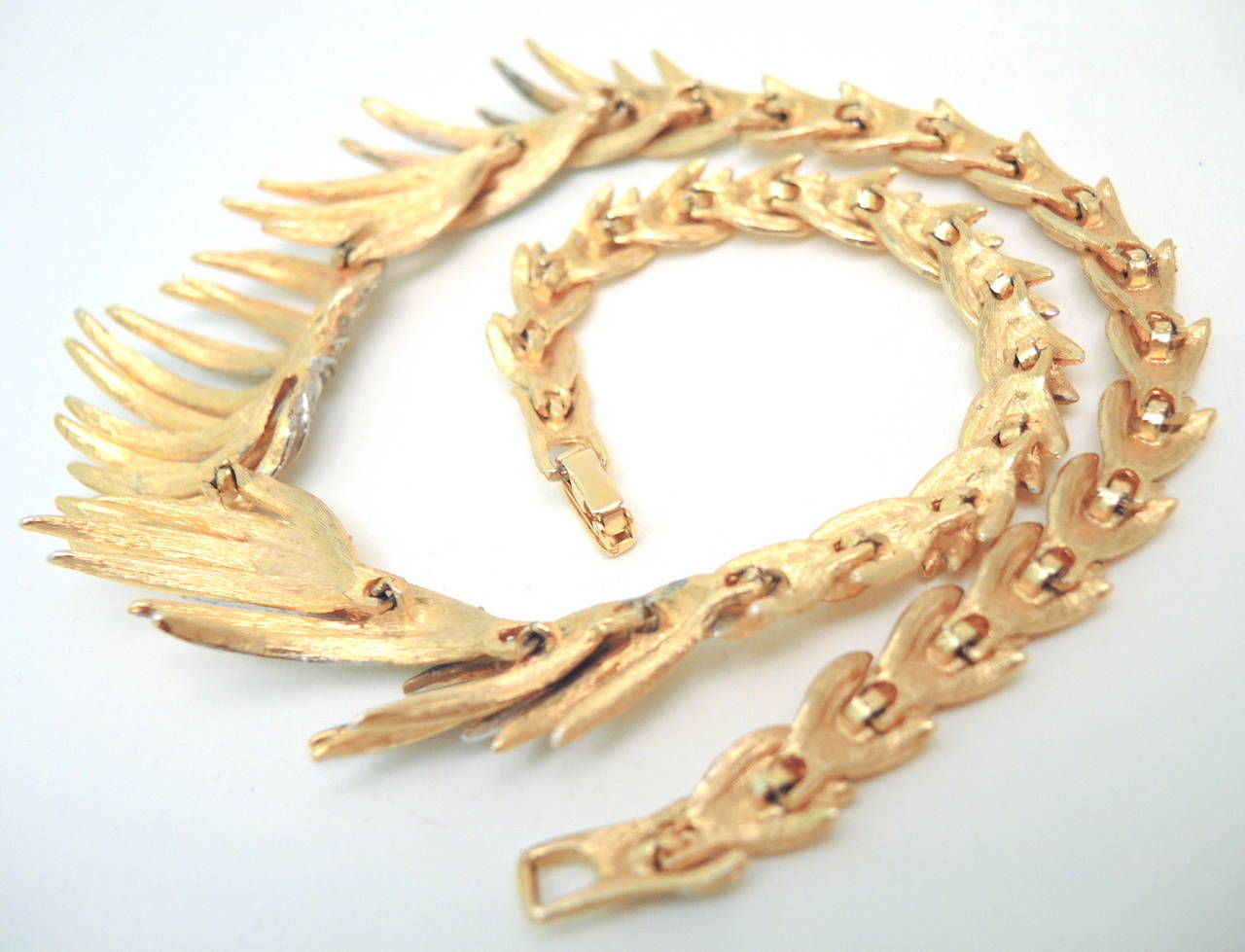 This vintage classic and collectible Trifari necklace features clear rhinestones in a gold-tone setting. This Trifari necklace measures 19” x 1 1/4” wide at the front and has a fold-over closure.