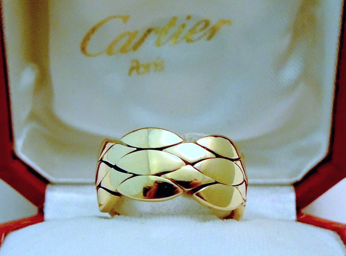 This classic, world recognized signed Cartier ring features a flexible basket weave design in 18kt gold .  A size 8, this ring measures 3/8” wide, is signed “Cartier 750 – E0022 54 – 1996”.