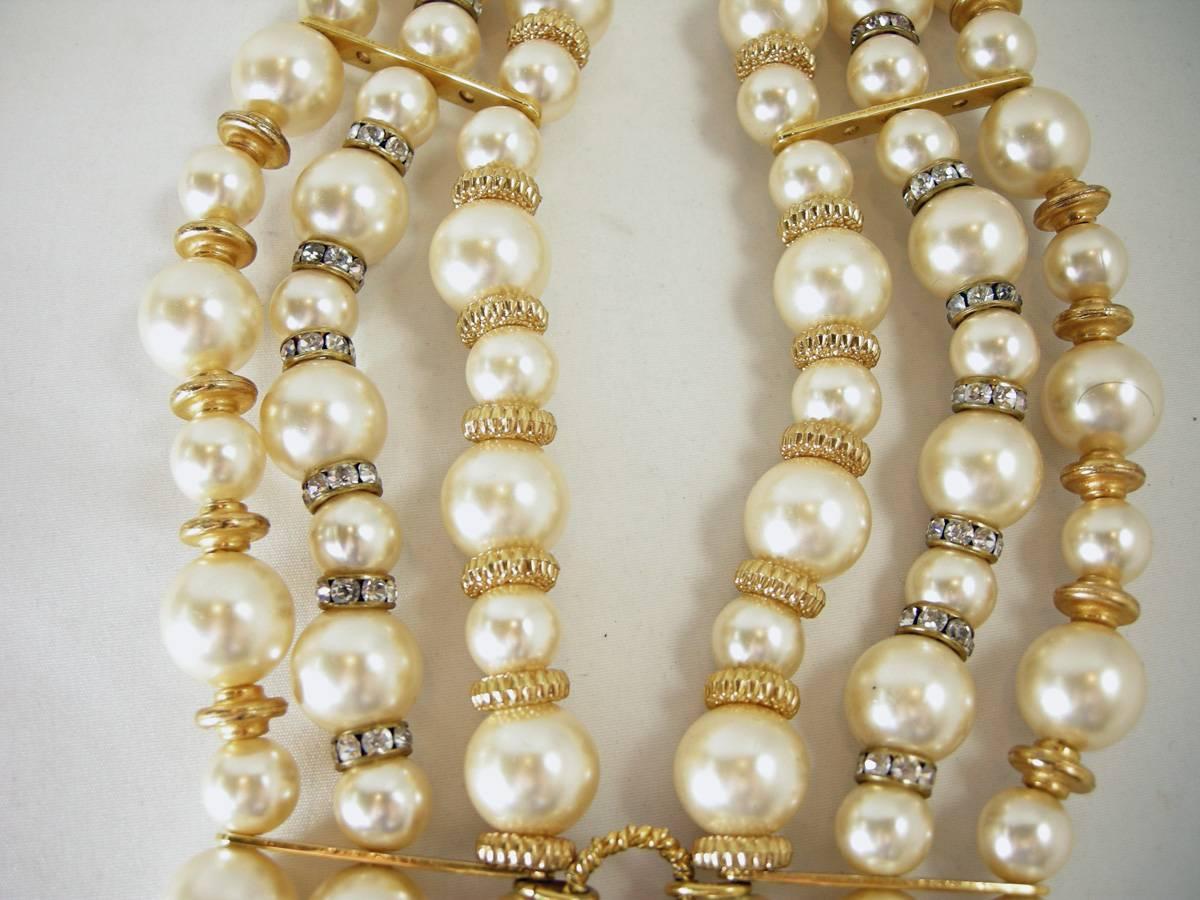 This vintage elegant cascading waterfall pearl necklace features 7 rows of large sized oval faux pearls with rhinestones and gold connectors in between each pearl.  Each strand has large sized faux teardrop pearls that dangle.  It measures 18” from