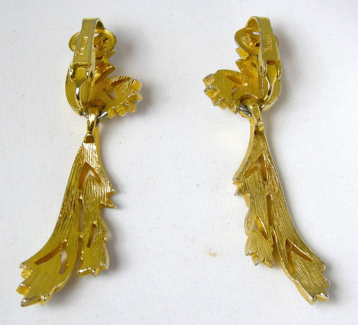 This is a stunning pair of vintage signed 1960’s clip Trifari hallmarked with the crown over the “T”.  They feature 5 delicate crystal leaves hanging down and embedded in a gold florentine metal finish. They are signed “Trifari” and measure 2-1/4” x
