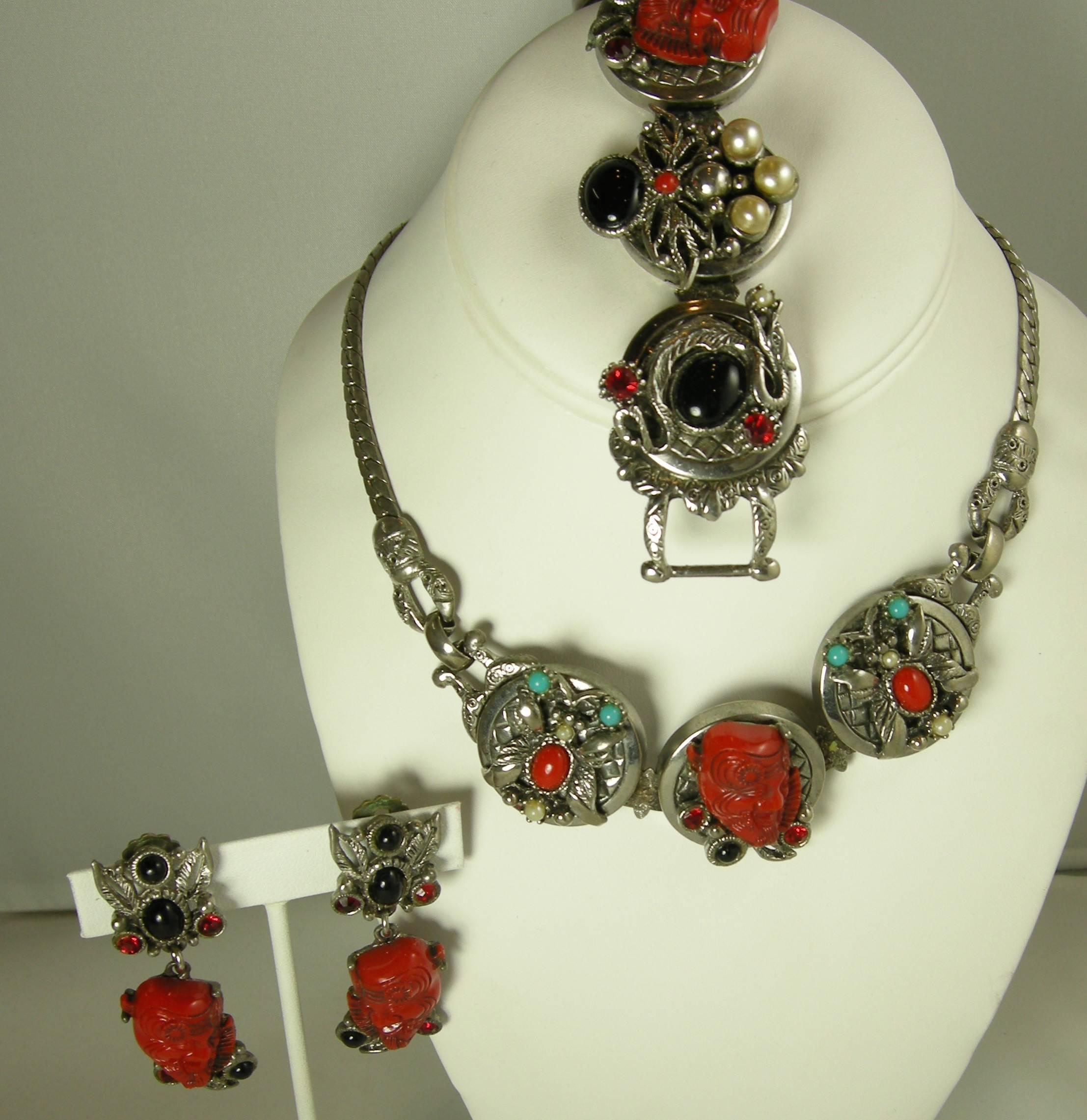 This very rare set is by Selro. The necklace features the famous red devil design with three charms. It has faux coral, as well as red, white, black cabochon stones accentuated with red crystals. The necklace chain measures 19” x 1/4” with the each
