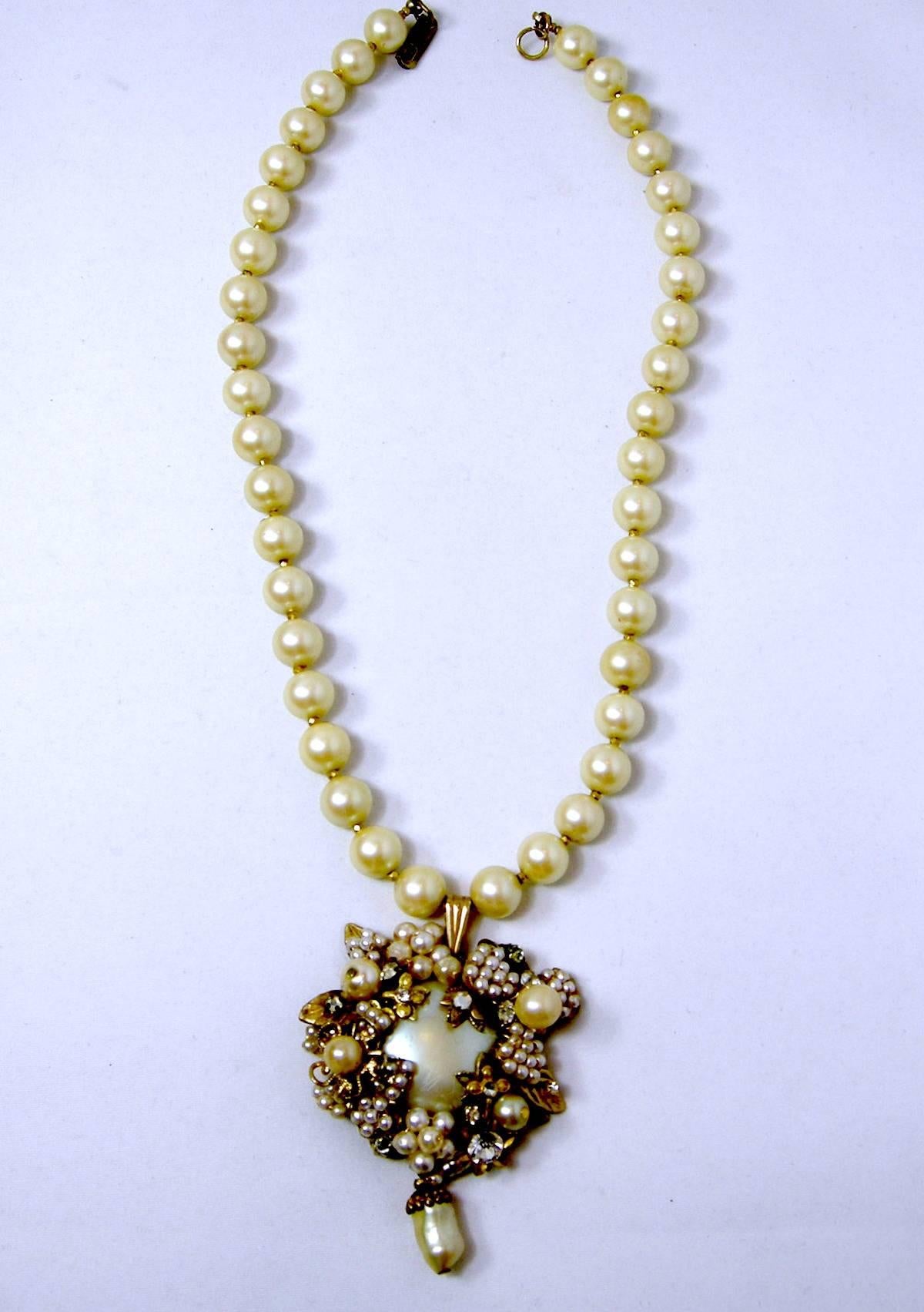 This vintage Miriam Haskell single strand necklace has beautiful cream-colored faux pearls with gold tone spacers in-between. It has a large sized faux pearl pendant. The long pearl pendant has multi-sized pearls with crystals accents and leaves. 