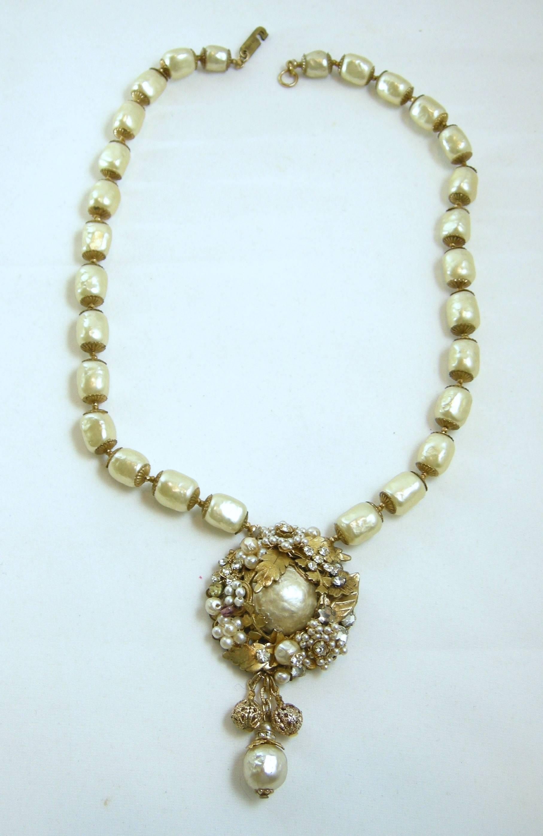 This Vintage Miriam Haskell necklace has graduated pearls that lead to a beautiful centerpiece with a large pearl. The large pearl has golden leaves with multi sized pearls and surrounding crystals. It has a large sized pearl dangling from the