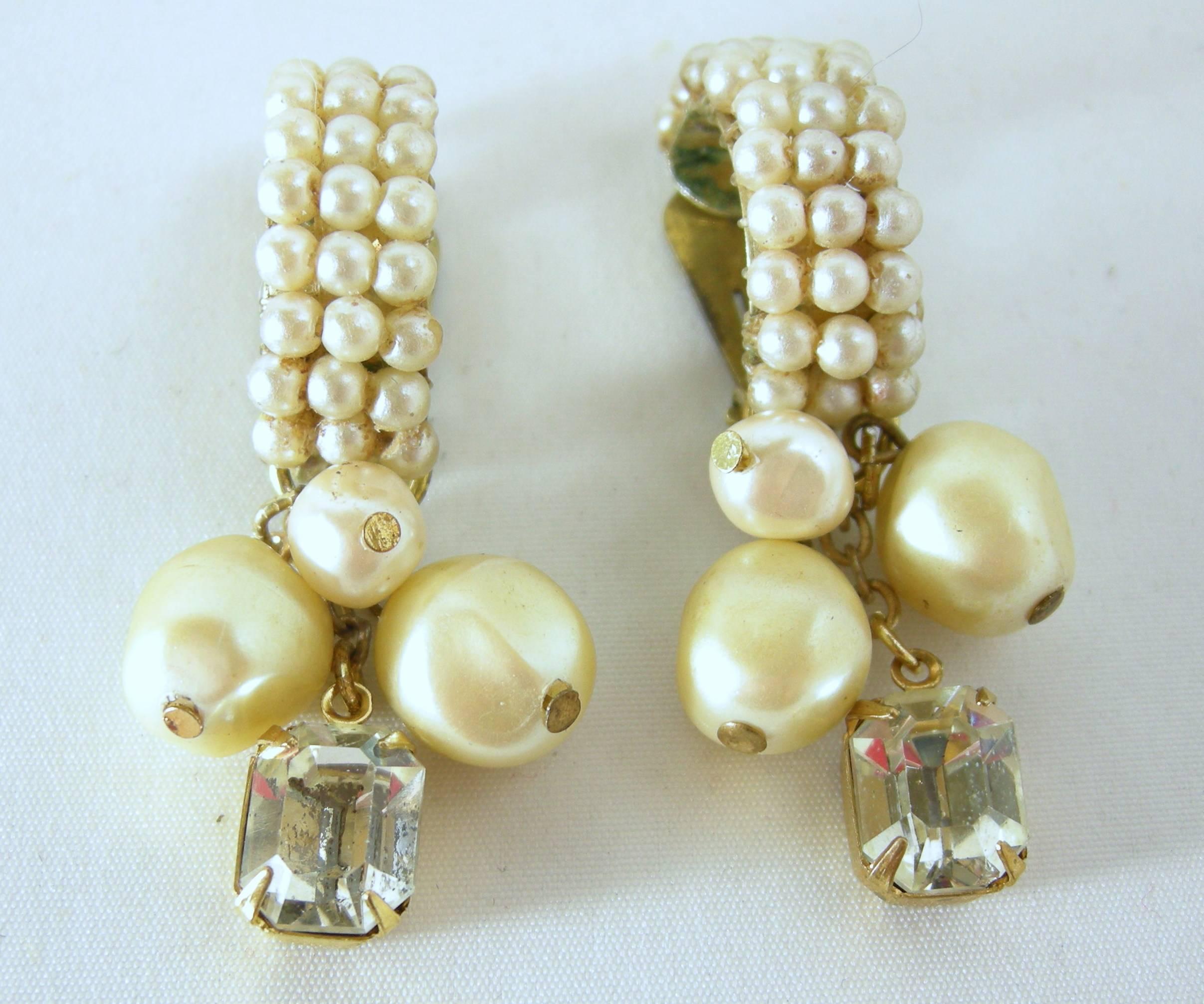 These shrimp shaped clip earrings are made with three rows of faux pearl seeds. It has three pearls that dangle and a large sized crystal. They are set in a gold tone setting and measure 2” x 3/8”. They are signed “DeMario” and in excellent