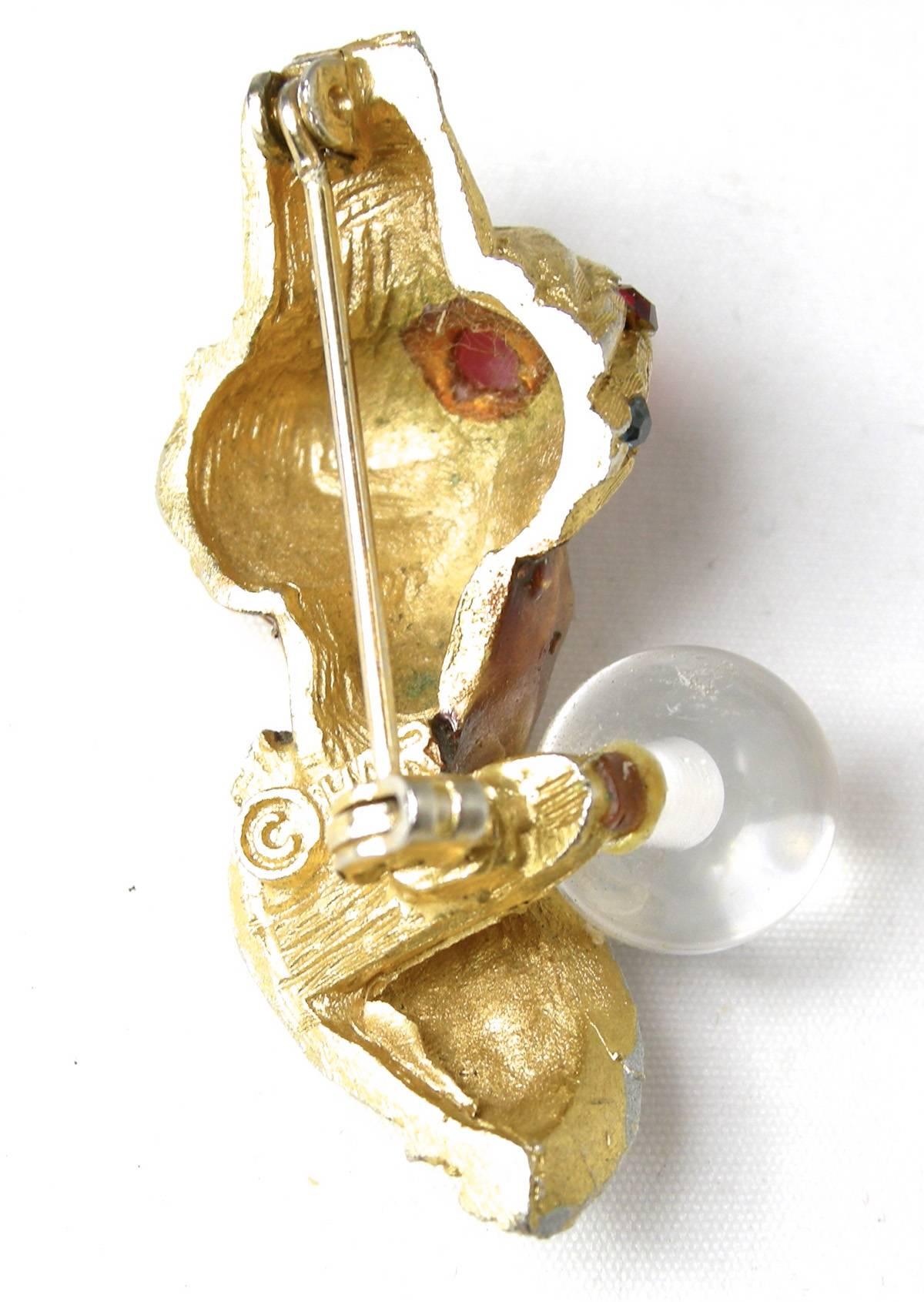 This is the famous 1950s vintage Har genie brooch holding his crystal ball. His turban has a red cabochon in the center and is accentuated with green, red and clear rhinestones.  It is set in a gold tone metal finish and measures 1-5/8” x 3/4”.  It