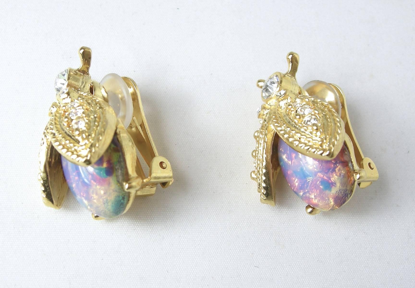 These signed Kenneth Jay Lane earrings feature a bee design with cabochon cut faux opal and clear rhinestone accents in a gold-tone setting.  In excellent condition, these clip earrings measure 1-1/8” x 3/4” and are signed “KJL”.