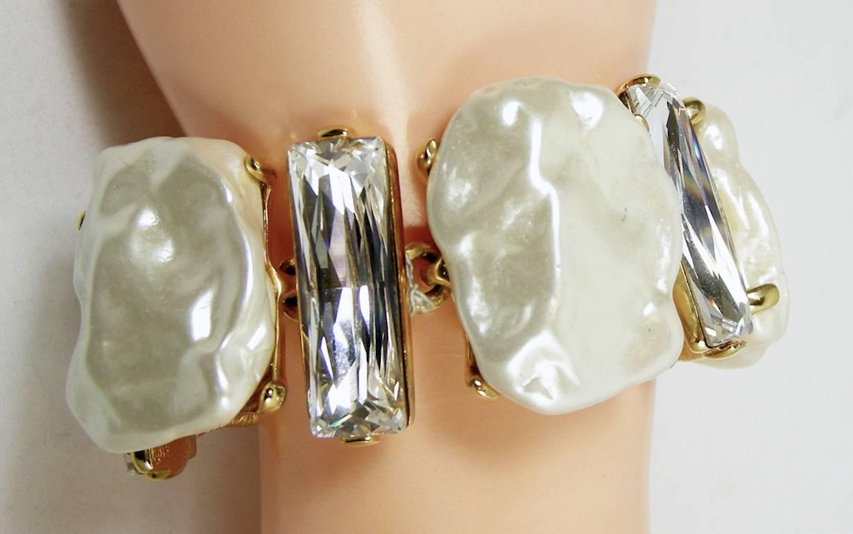 This signed Kenneth Jay Lane bracelet features 3-dimensional faux pearl discs in a gold-tone setting.  In excellent condition, this bracelet measures 7” x 1-1/4” with a fold-over closure and is signed “Kenneth Lane”.