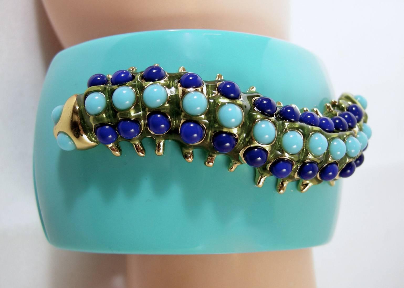 This signed Kenneth Jay Lane clamper bracelet features faux turquoise plastic with a caterpillar centerpiece with faux lapis & turquoise stones in a gold-tone setting.  In excellent condition, clamper bracelet measures 7” x 1-3/4” and is signed