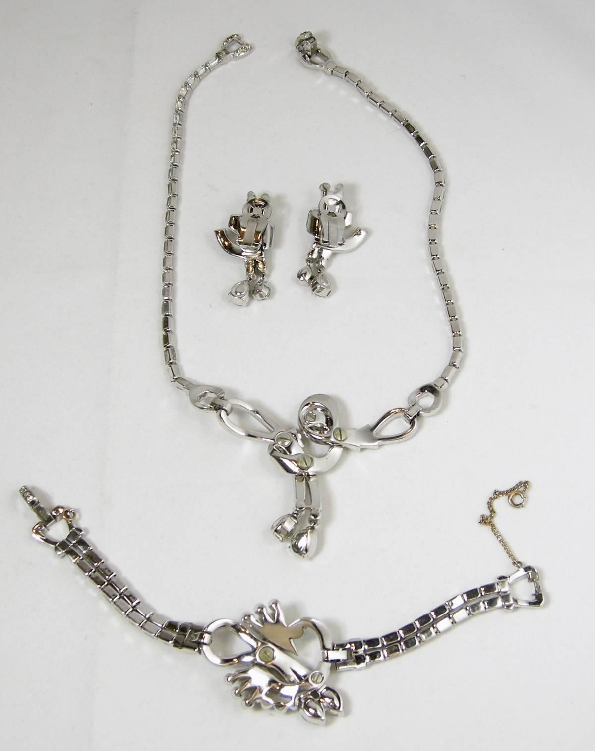 This is a very rare parure set by Mazer Brothers from the 40s.  It features clear crystal in a silver-tone rhodium setting.  The  necklace measures 16” long with a fold-over clasp and a front drop of 2-1/8” long/top to bottom.  The bracelet measures